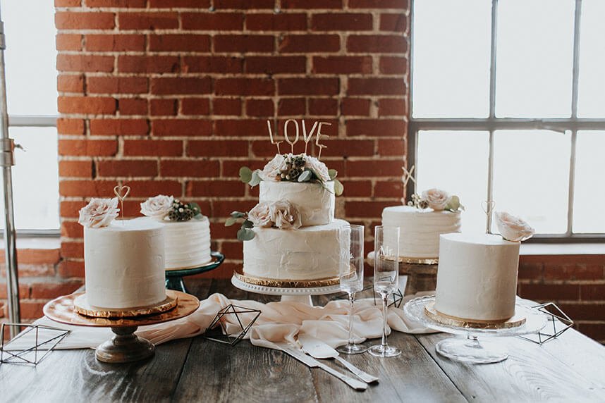 Event venue interior showing branded space in use with wedding cake display, florals, and exposed brick backdrop