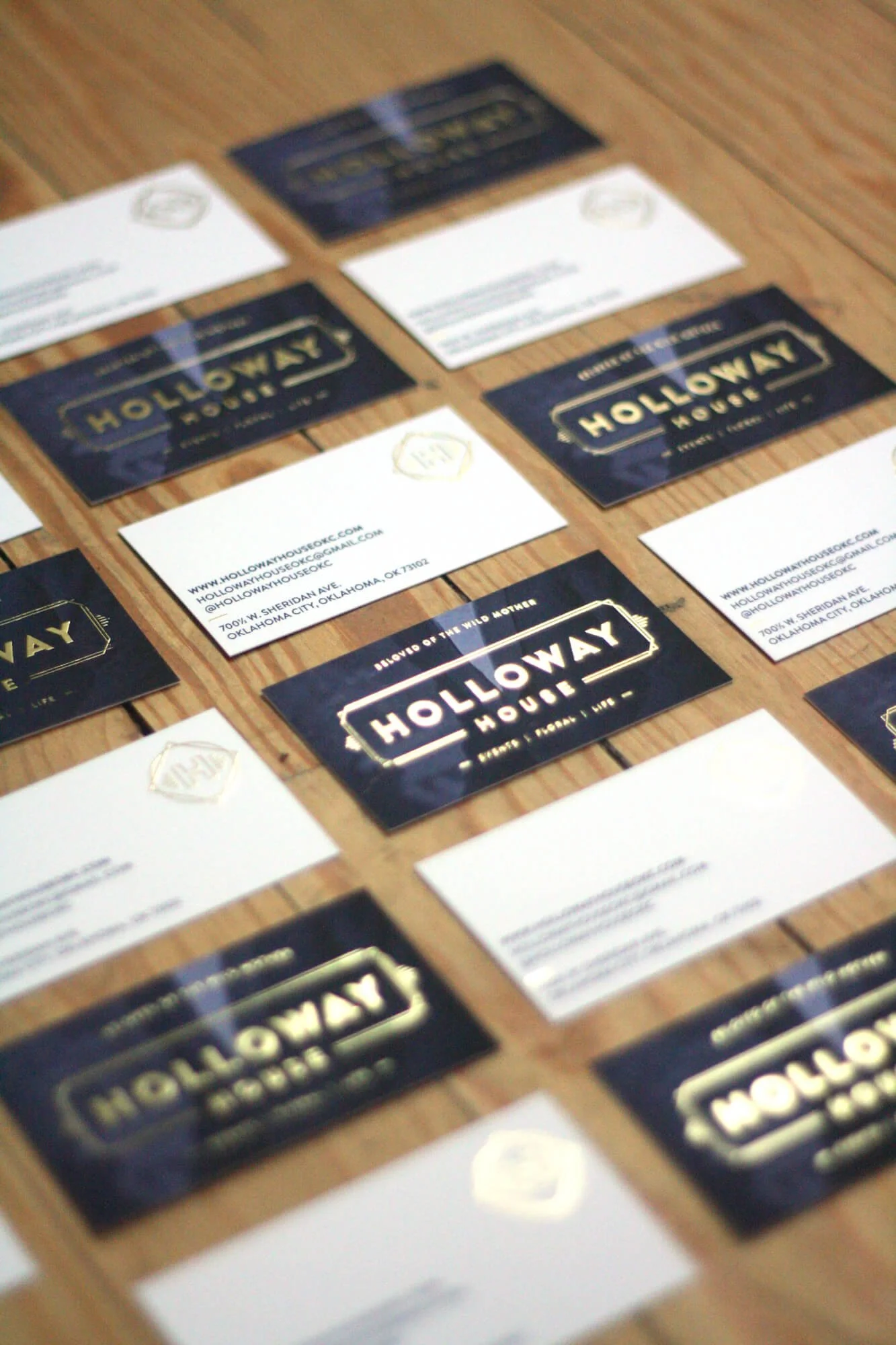 Holloway House business cards and branded stationery arranged on a wooden tabletop, showcasing the venue’s logo, contact information, and visual identity.