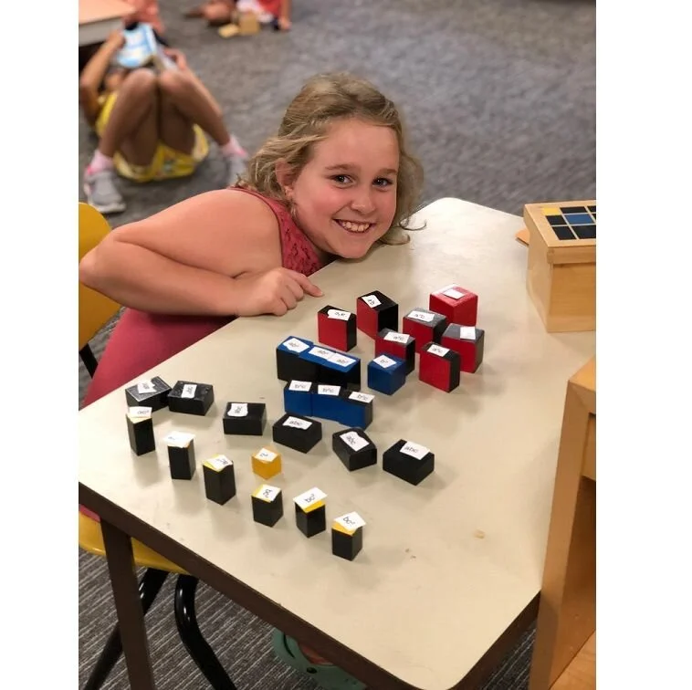 A third-grade-student labels the shapes of the Trinomial Cube to understand the mathematical equation that the material represents. She would have first used this as a 3-D puzzle in the Children’s House, absorbing the information by repeatedly creating the cube.