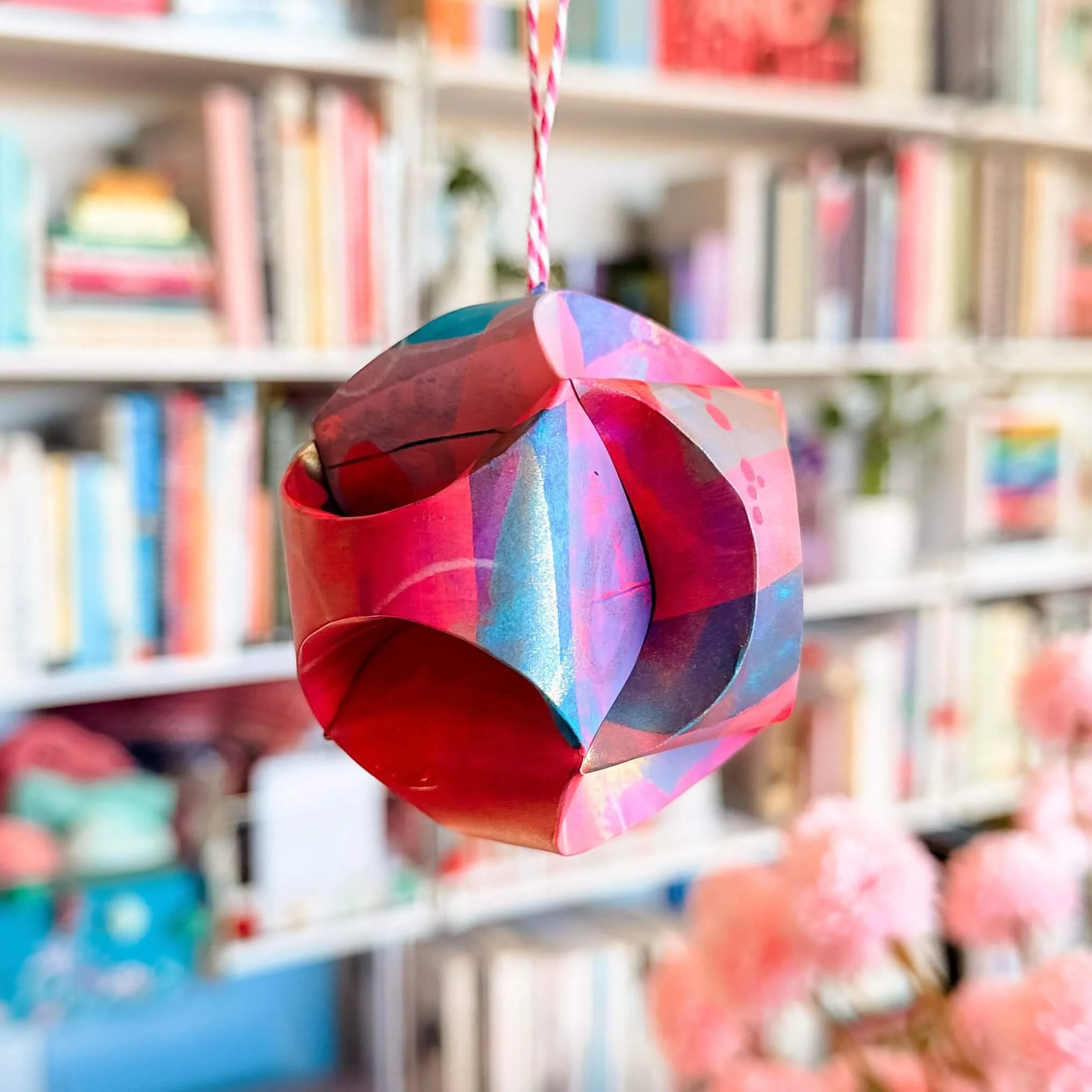 Easy DIY paper ornament for Christmas tree in front of bookshelf