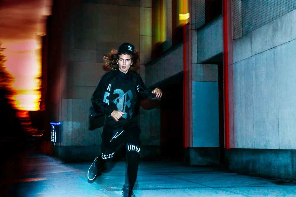 Woman in black athletic wear running at night in an urban area with modern buildings and colorful lights.