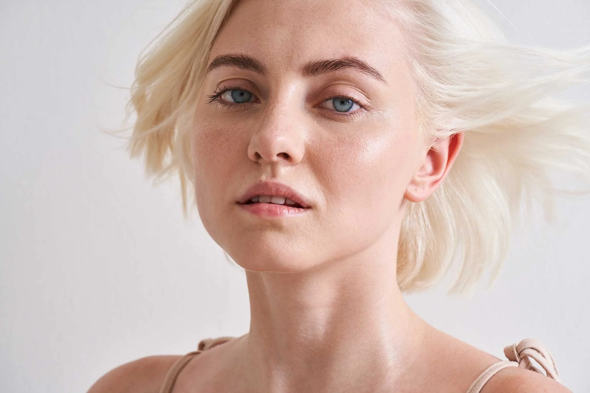 Close-up of a woman with short platinum blonde hair, blue eyes, and fair skin, looking at the camera with a neutral expression.