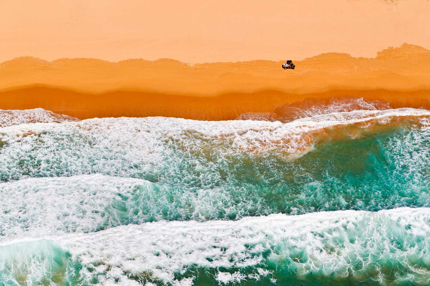  Aerial photograph of a Surf Life Saving vehicle cruising up the shoreline of Whale Beach,NSW. 