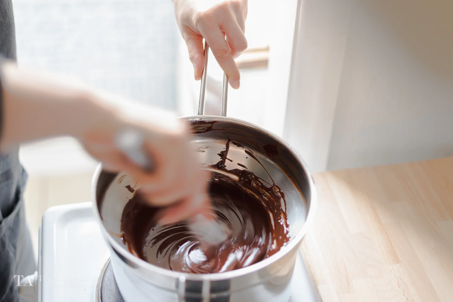 Stirring melted dark chocolate on a stove.