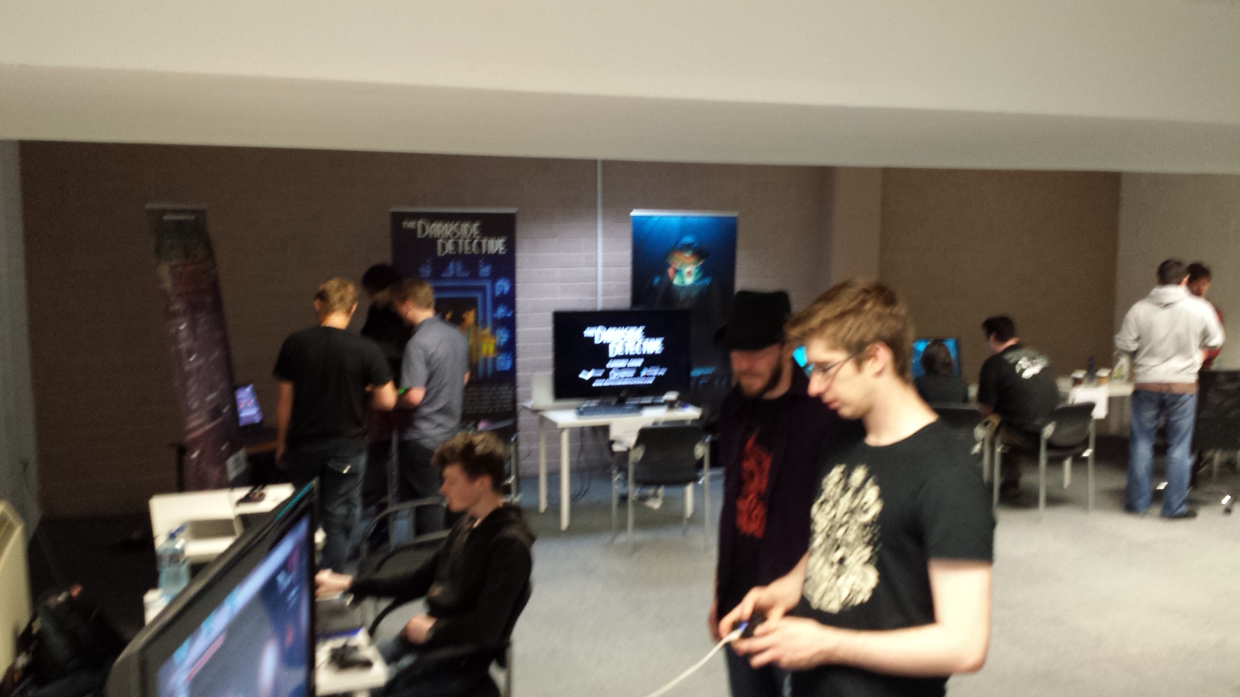 Indie gamers show their wares, with Onikira on the big screen, and Goblin's Grotto, Darkside Detective and Trench visible in the background.