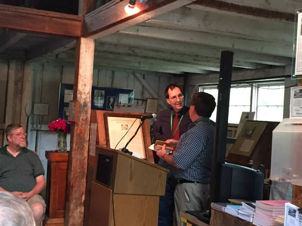 Director Robert Crawford presents Bill Baer with a gift pen made from a maple tree that grew on Frost's farm