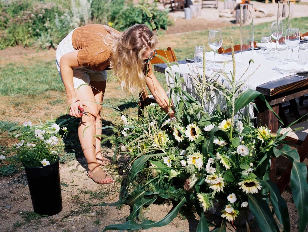 Freelance Designer Adin placing a sunflower in arrangment