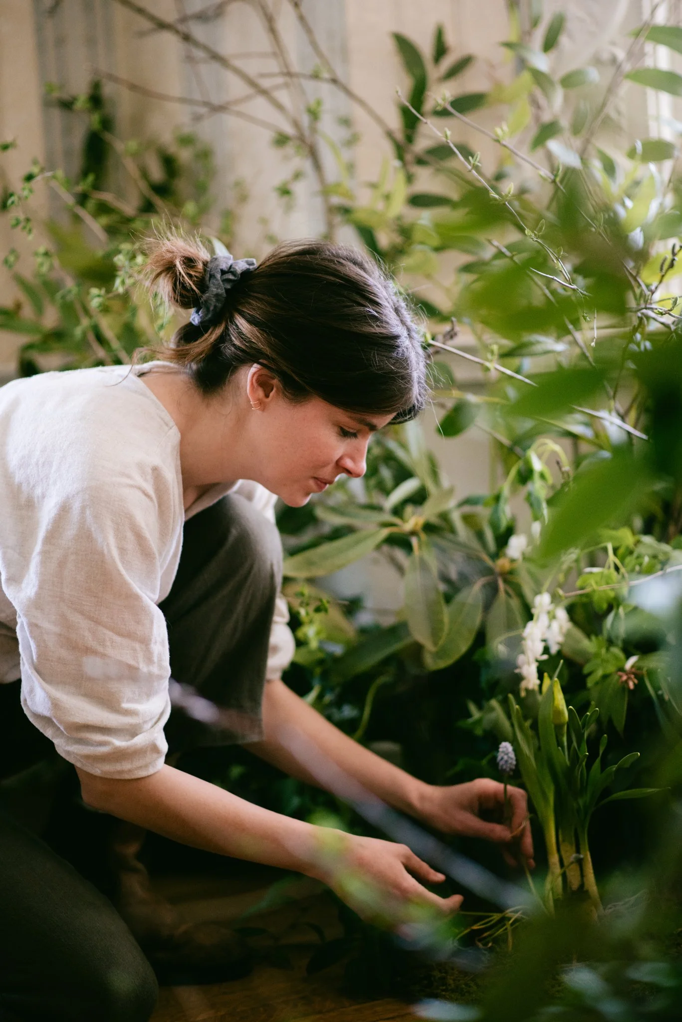 owner Emily kneeling while placing a muscari in design