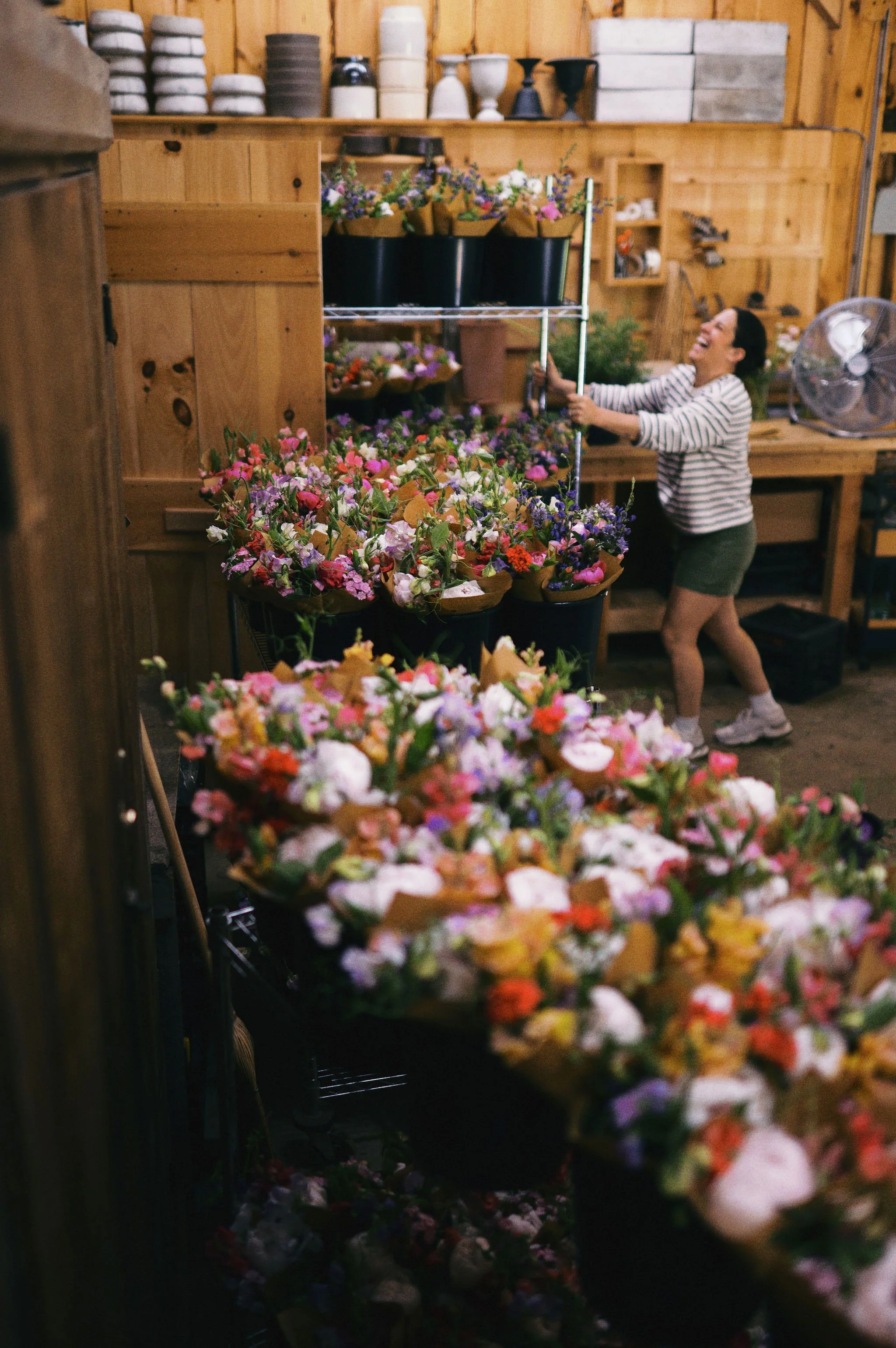 Freelance designer pushing cart of bouquets into walk-in cooler