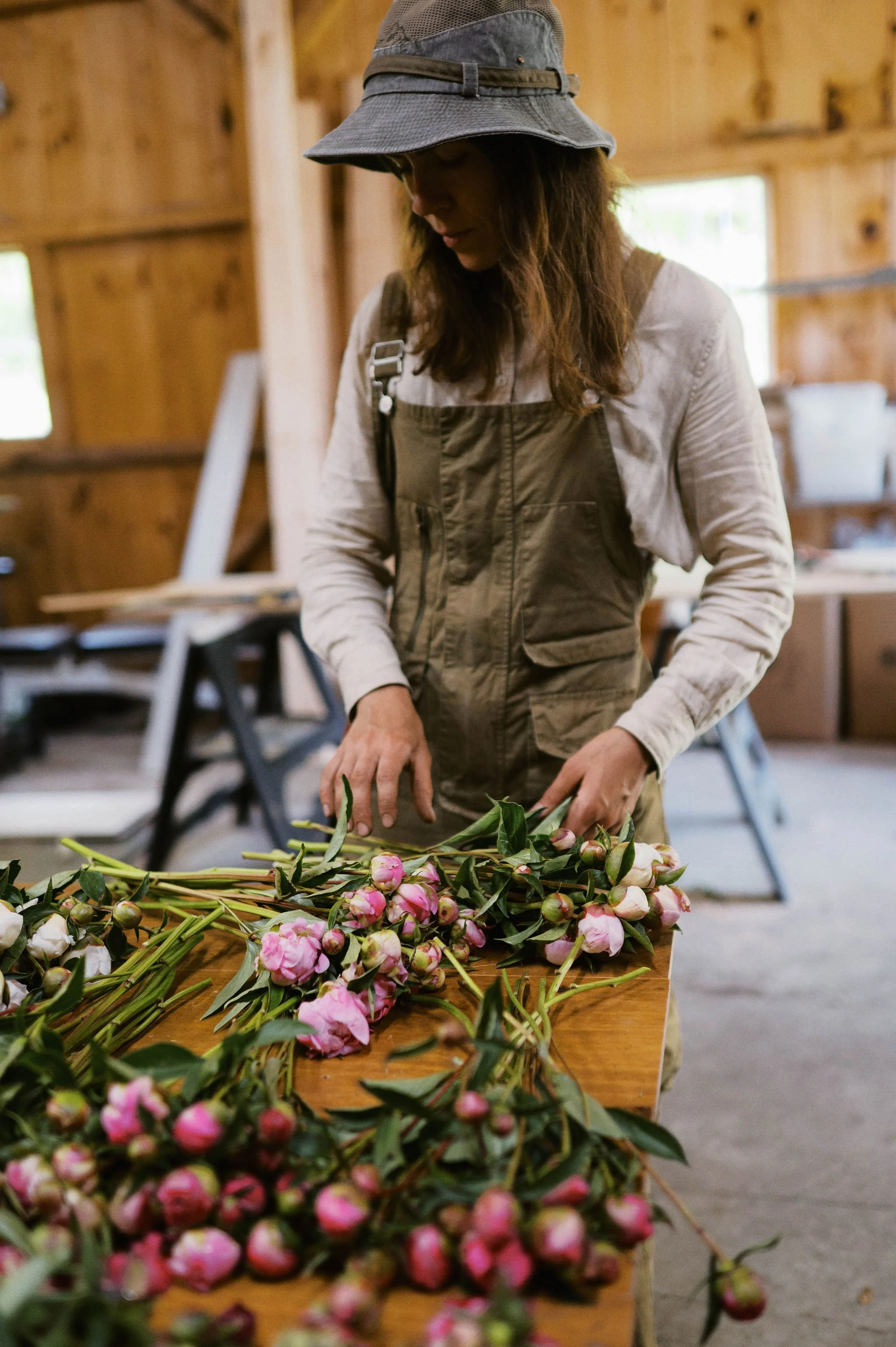 employee lily standing with peonies in barn