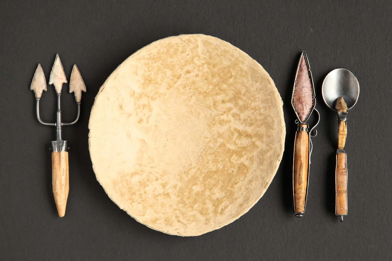 STONE SETTING of silver, stone, Eskimo tool fragments. This setting at 17.78 x 27.94 centimeters includes the plate; spoon is 12.7 x 2.86 centimeters. The clay paper plate was made by Arte Papel Vista Hermosa, Oaxaca, Mexico.