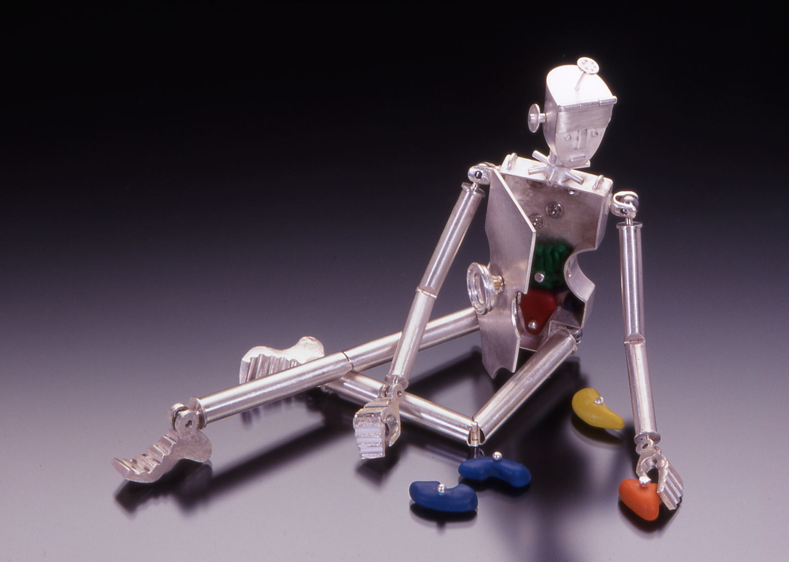 PUZZLEGUTS NECKPIECE of sterling silver, eighteen and twenty-four karat gold, nickel silver, steel snaps, plastic, polymer clay, fabricated and cast, 20.2 x 5.1 x 2.5 centimeters, 1999. Photograph by Doug Yaple.