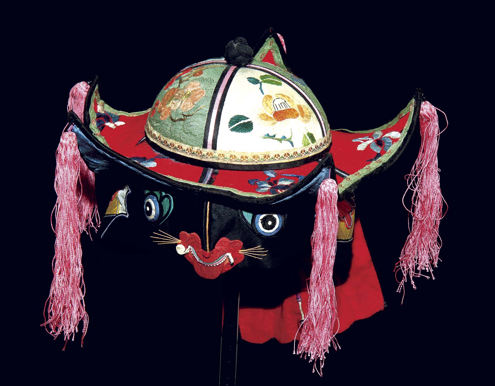 TIGER HAT COMBINED WITH SCHOLAR’S HAT, a beautiful example of textile arts and symbolism, 15.0 centimeters wide. These hats were photographed in an improvised studio, on a brass armature, with a black Tufflock backdrop. They were lit with an external flash on a Canon 7D, with or without additional slipon diffuser, besides the Speedlite 580EX’s own translucent diffuser. When we felt the armature was too obtrusive, it was removed using the Photoshop clone tool (Liu 2014). Pam Najdowski Collection. Photograph by Robert K. Liu/ Ornament .