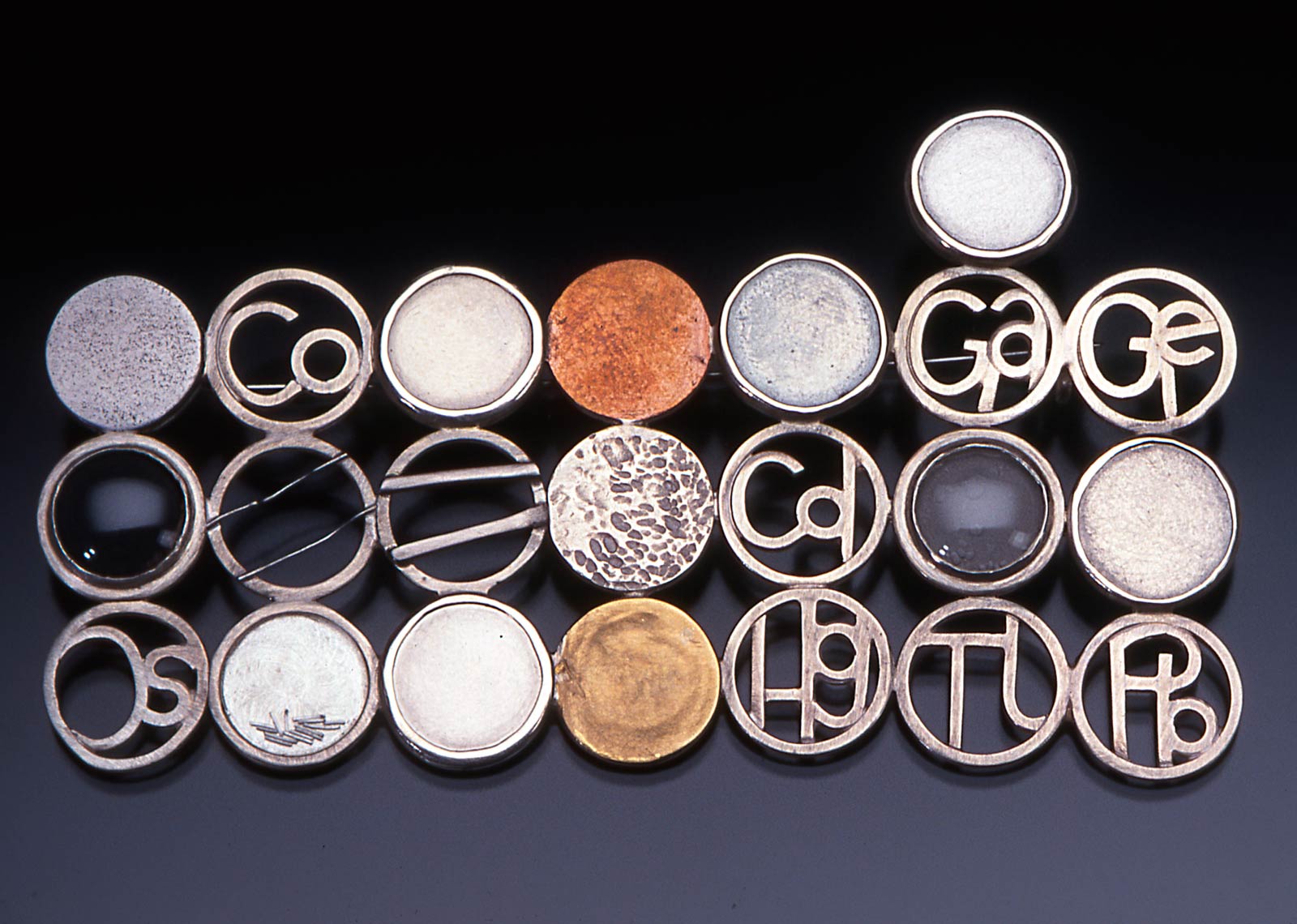 TRACE ELEMENTS 1 BROOCH of fabricated sterling silver set with aluminum, iron, nickel, copper, zinc, ruthenium, rhodium, palladium, silver, indium, tin, iridium, platinum, gold, 8.4 x 4.5 x 0.5 centimeters, 2000.