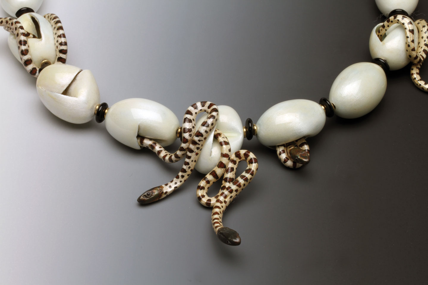 STUDY OF NORTHERN BLACK RAT SNAKE NECKLACE, closeup showing eggs and hatchlings, of enamel over fine silver, with gold jumprings and Czech glass beads. Multiples of this necklace have been made from 1984 to 2000, his only limited production design; this necklace is 24.1 centimeters long, with eggs 2.7 cm each. The late Barbara Rockefeller owned the first snake egg and hatchling necklace made by Freda. Mobilia Gallery Collection. 