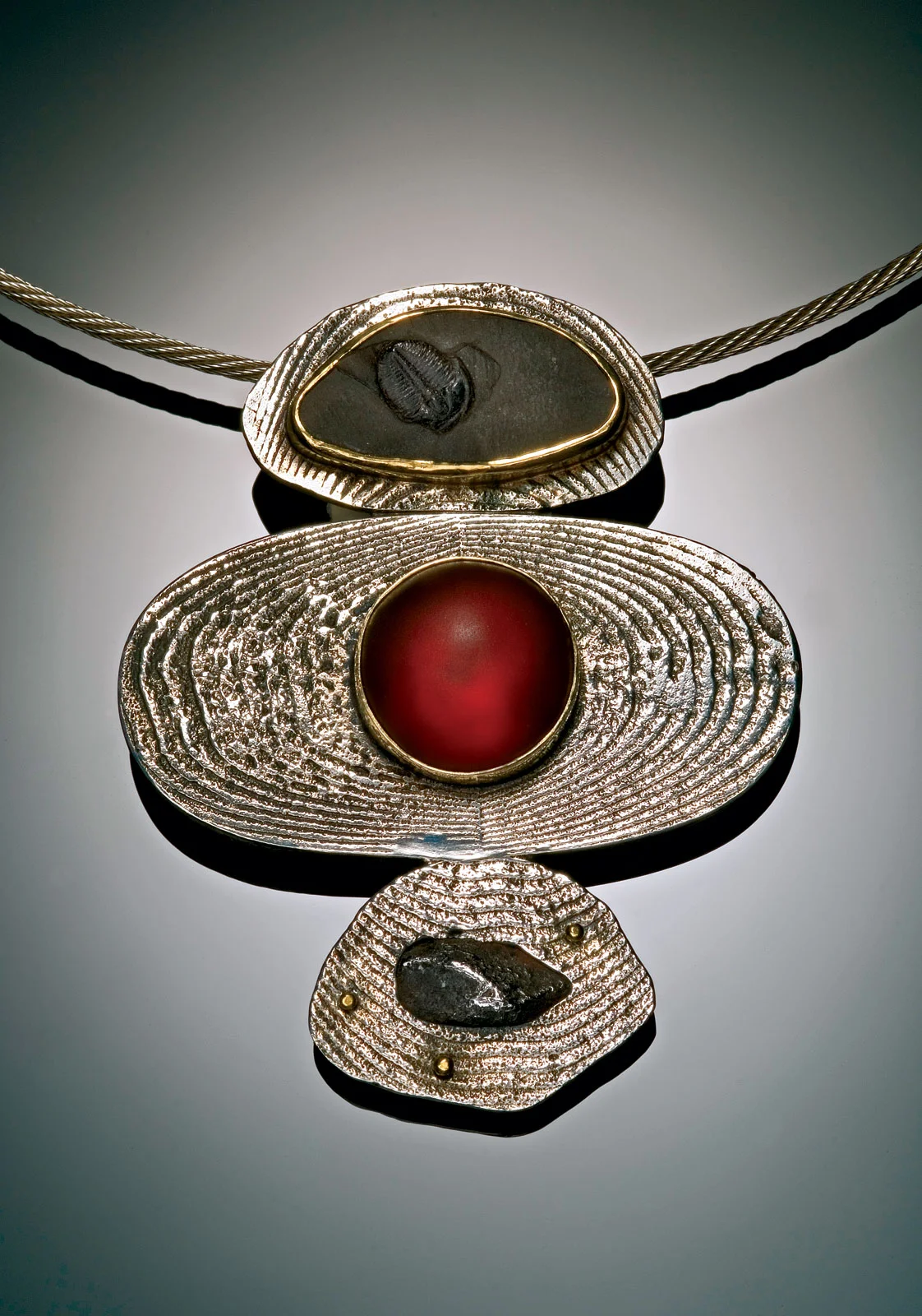 LIFE ON MARS BROOCH/PENDANT of sterling silver, eighteen and twenty-two karat gold, glass, slate trilobite fossil, meteorite, 7.0 x 5.1 x 1.3 centimeters, 2000. Photograph by Walker Montgomery.