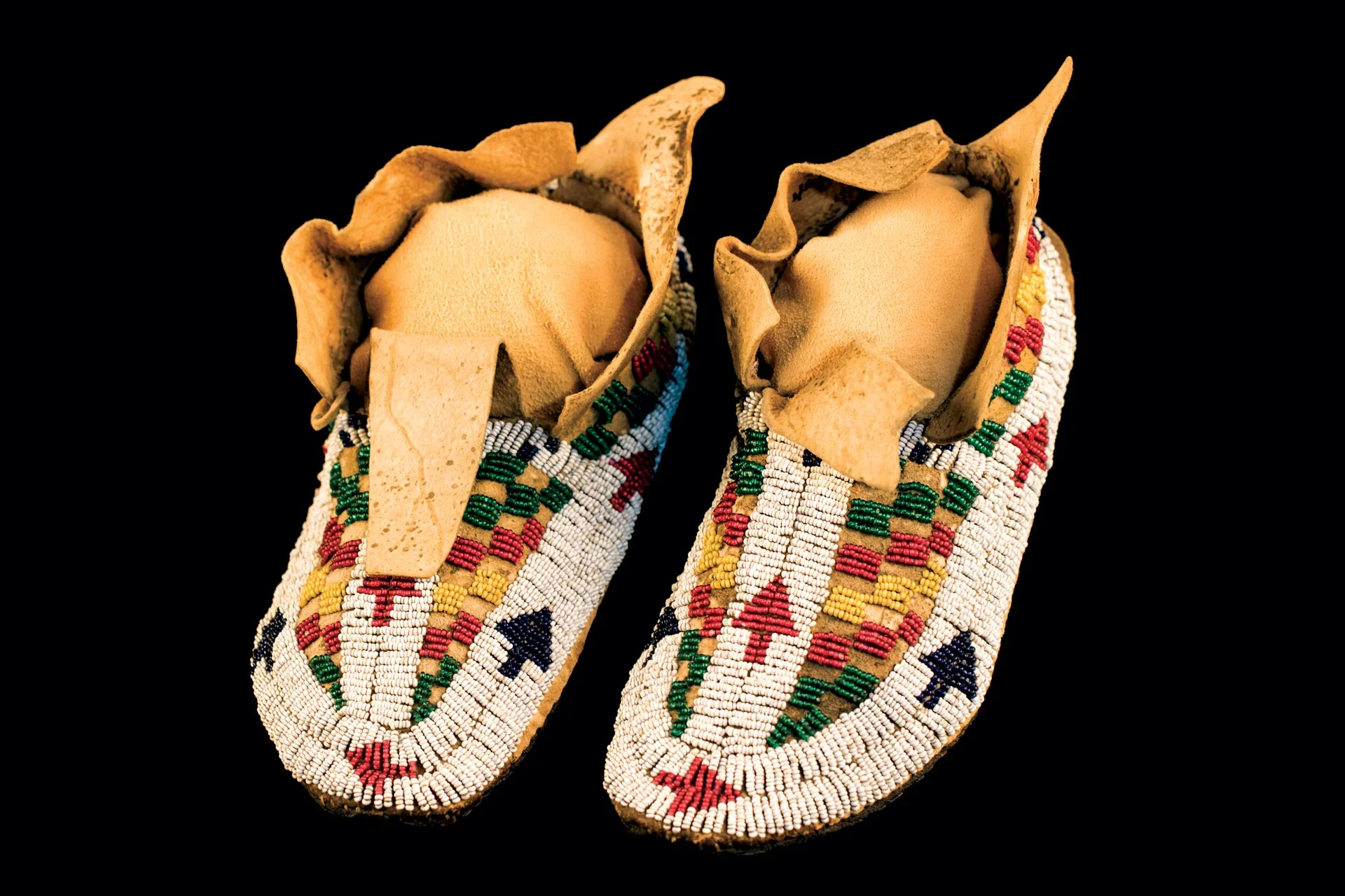BOY’S MOCCASINS (Northern Cheyenne) of buckskin, rawhide, glass beads, sinew, 1875-80. The small and somewhat irregular white beads on these moccasins help date them.