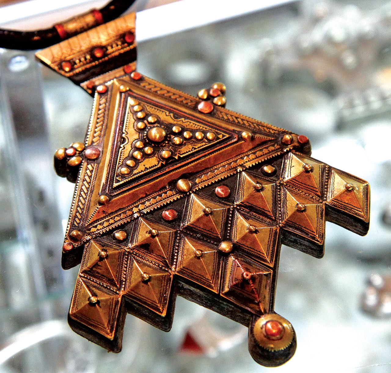 CONTEMPORARY VERSION OF TRADITIONAL TUAREG HAMSA/KHOMESSA. Niger, fabricated, of brass, copper and leather. It is the melding of a triangular amulet and a doubled hamsa, although with two more elements, so as to make the design symmetrical. Both the triangle and hamsa offer protection. While this pendant is new and in base metals, there is still a good level of crafting. Courtesy of Ethnic Embellishments.