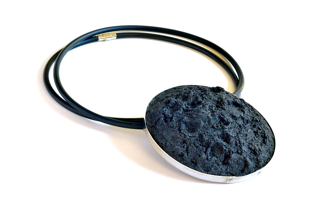 DARK SIDE OF THE MOON NECKPIECE of stainless steel, concrete, dye, and rubber, pendant 10.0 x 4.0 centimeters, rubber cord 107.0 centimeters, 2017. Photograph by Barbara Cohen.