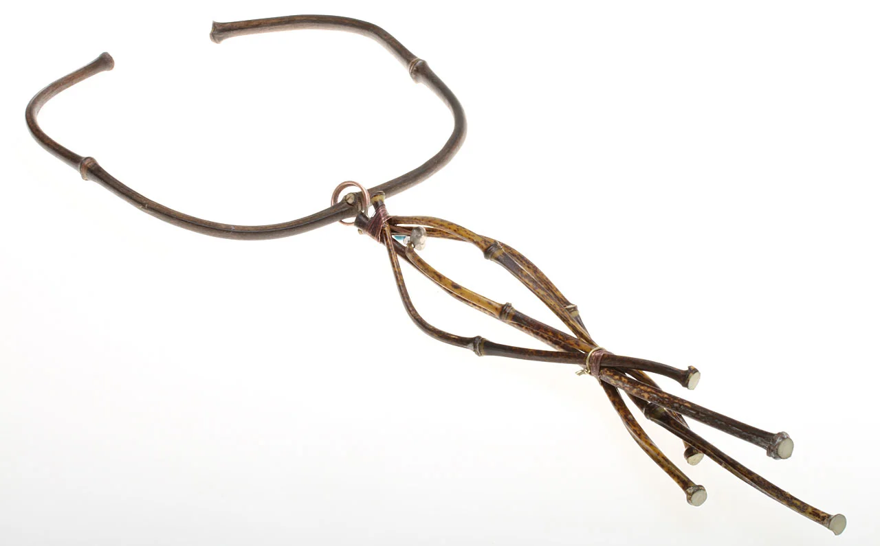 IN PROGRESS VIEW OF VERTICAL JIGGED PENDANT ON BAMBOO TORQUE, showing it attached by a soldered copper loop, meant to rest in a groove filed into the center node of the torque. Each of the ends of the culm that will be decorated with beads or balls are burred prior, so that the attachments sit in a depression and not on the surface of the culm node.