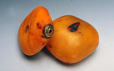 Mauritanian copal bead with decoratively reinforced perforations and Tibetan copal inlaid with coral. RKL