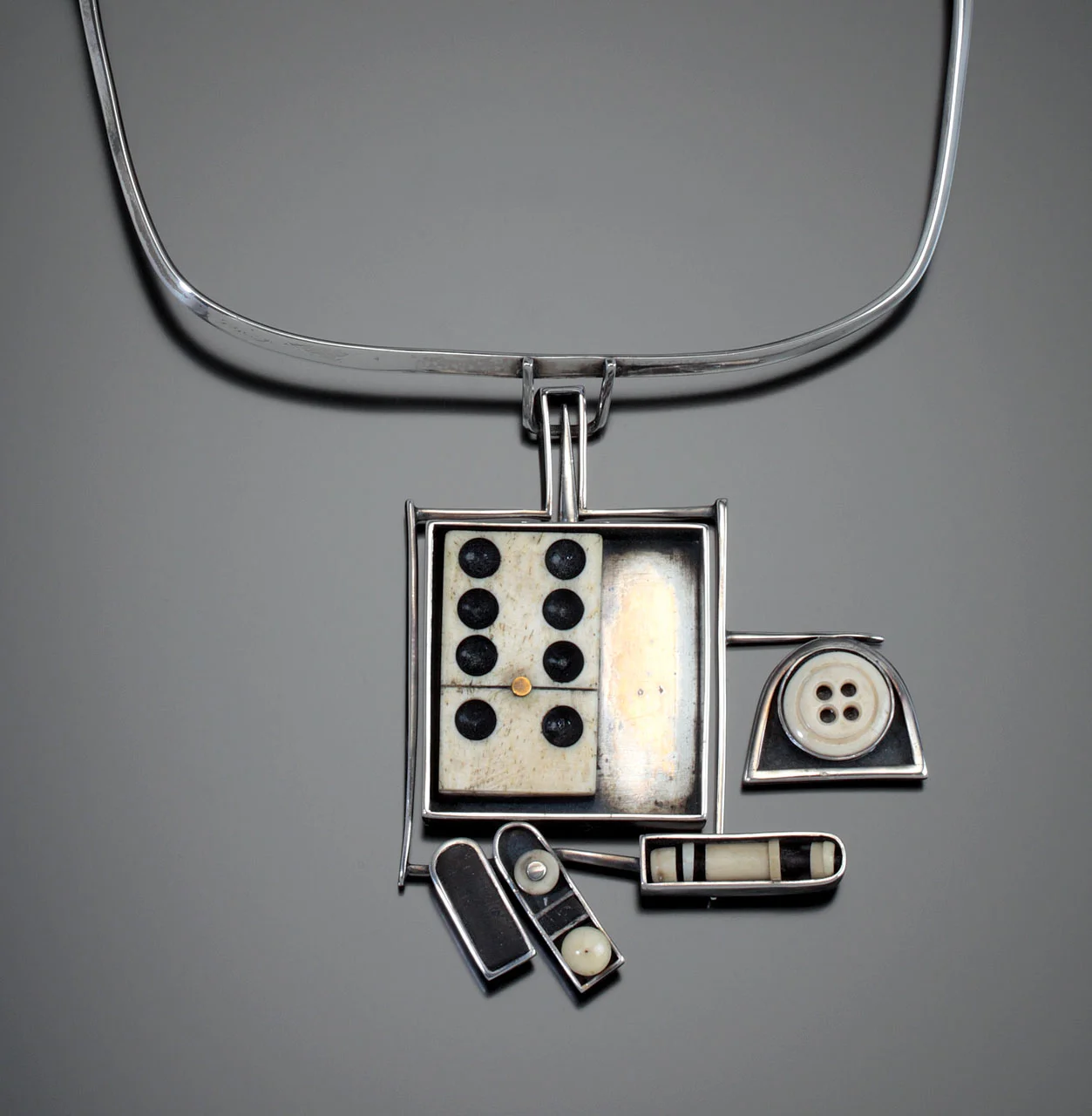ALL FALL DOWN II NECKPIECE of silver, ebony, domino, and found objects, 1981. A breakthrough for Ho was represented by this gift to Ramona Solberg. “One evening Ramona brought me an ivory domino piece and some old bone underwear buttons. I placed these on a piece of paper with some bone heishi beads and some pieces of ebony. It was the beginning foundation of my work as a jewelry artist.”