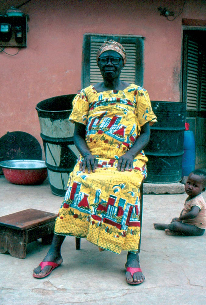 IN A VILLAGE NEAR BROBO, CÔTE D’IVOIRE, an unidentified woman wears a wax-print featuring the distinctive skyline of Abidjan, 1992. The three-piece complet , made from six meters of printed cloth, is considered by many to be traditional Ivorian dress and is associated with propriety, discretion, moral fortitude, and a high regard for tradition. Photograph by Kathleen Bickford Berzock.