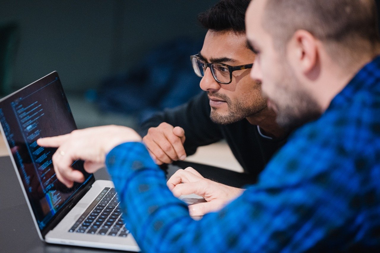  zwei software entwickler schauen konzentriert auf einen monitor am notebook und diskutieren über den code 