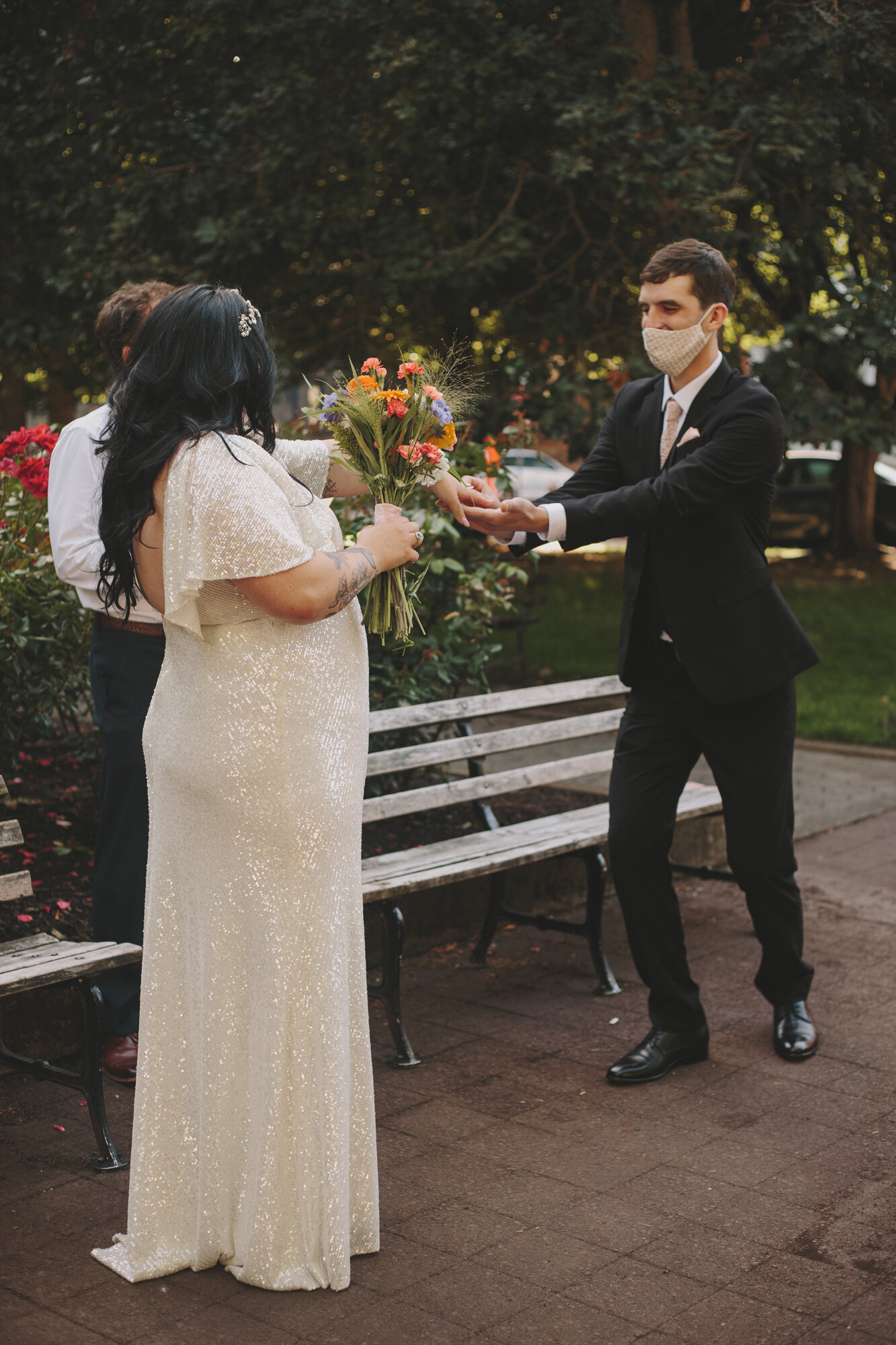 Bride and groom wearing face masks exchange rings during wedding ceremony