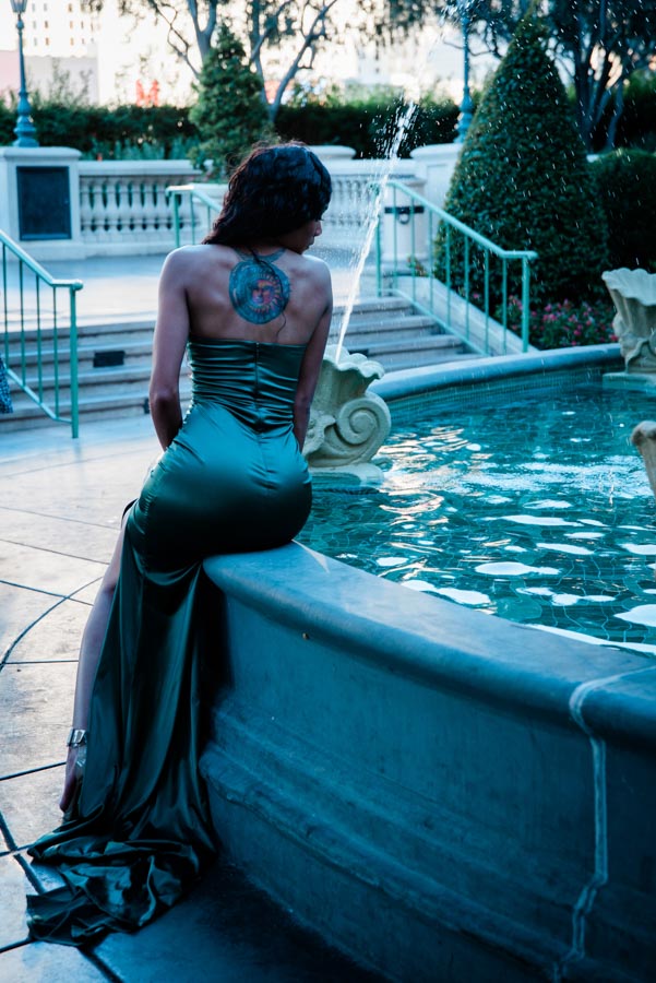 elegant woman with back tattoo looking at fountain