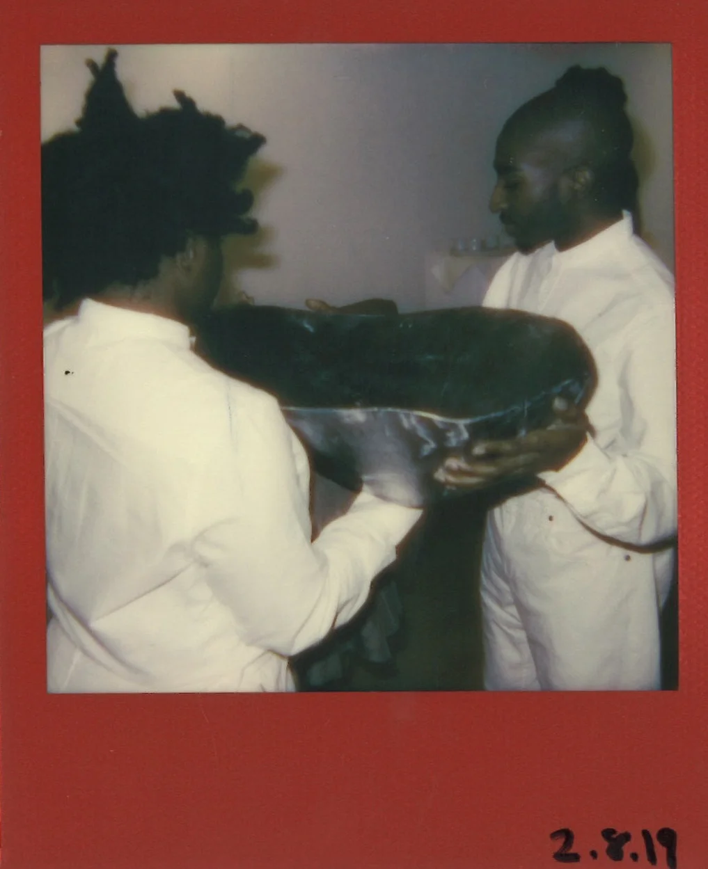 Performance artists Ashley Shey and Maps Glover hold Yacine’s Fall’s spoon as she unties herself from the 70-pound steel piece. Polaroid for ‘ FED ’ by Maxwell Young
