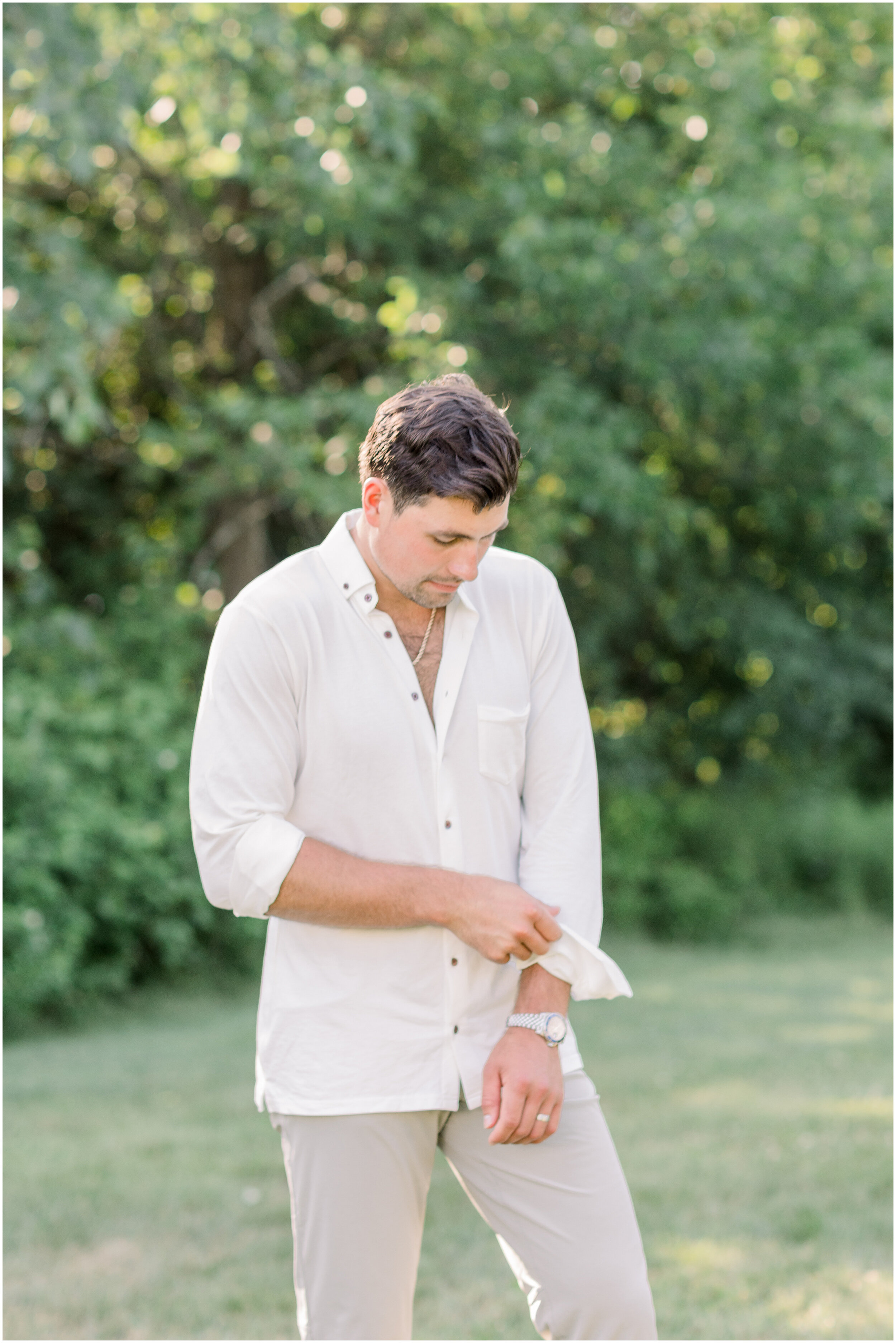 Handsome groom wearing casual boho wedding clothes with a white botton down shirt and khaki pants in Ottawa, ON by Chelsea Mason Photography. boho wedding outfit inspo outfits for grooms for boho wedding casual groom outfit for backyard wedding groo