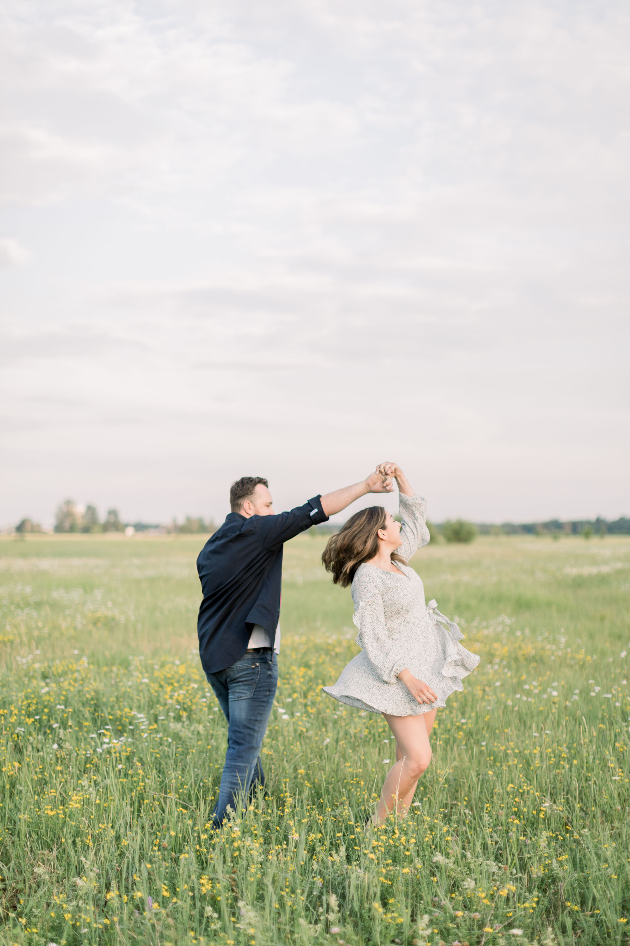  Adorable engagement candid shot of couple dancing in a green field during a spring photoshoot in Ottawa, ON by Chelsea Mason Photography. candid couple photos poses for engagements best locations for spring photoshoot in ottawa outfit inspo for enga