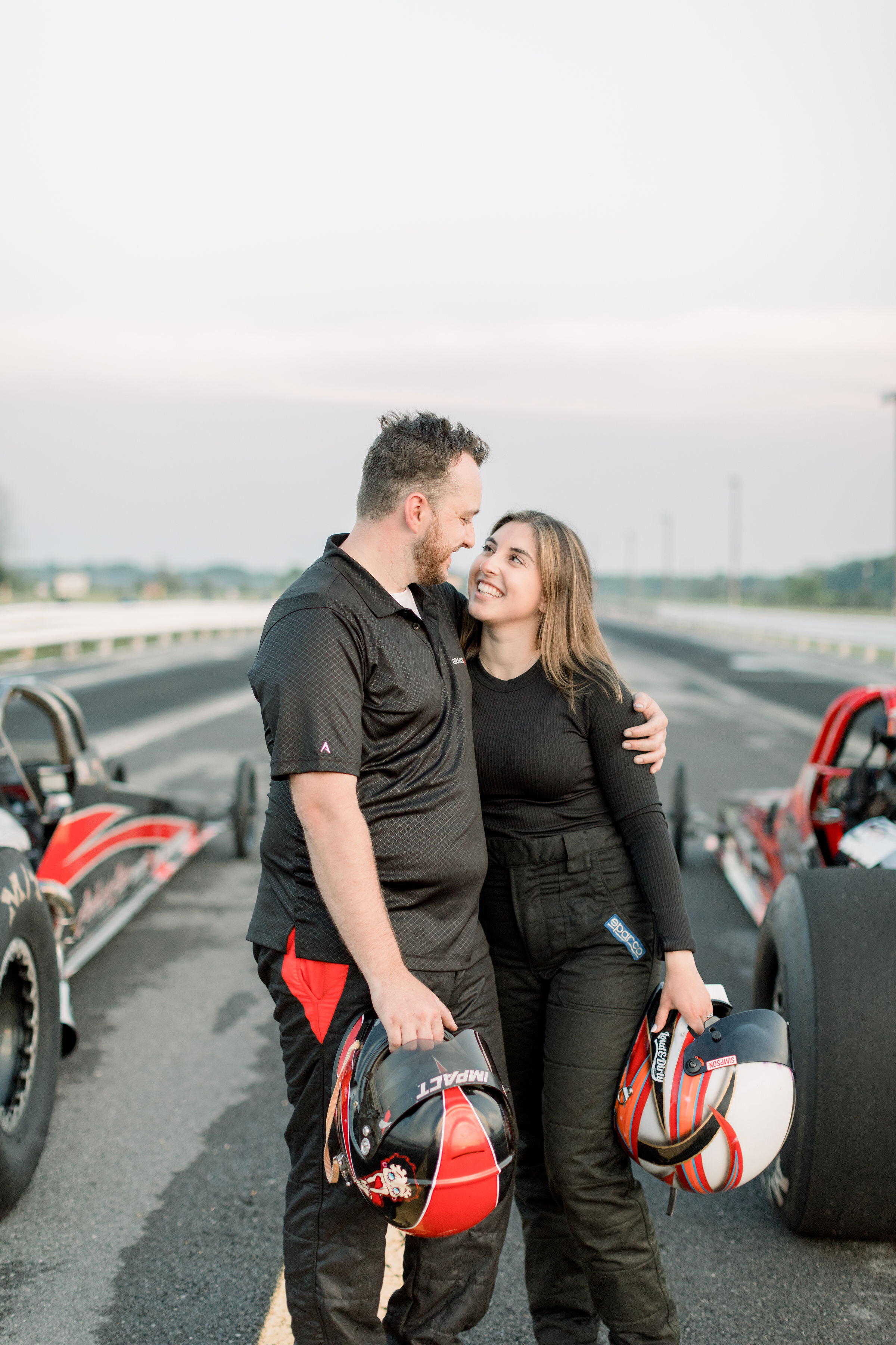  Beautiful couple wearing racing gear and holding race helmets in this fun engagement photoshoot by Chelsea Mason in Ottawa, ON. fun engagement photoshoots fun poses for couples props in photoshoots fun outfits for engagement photoshoot best wedding 