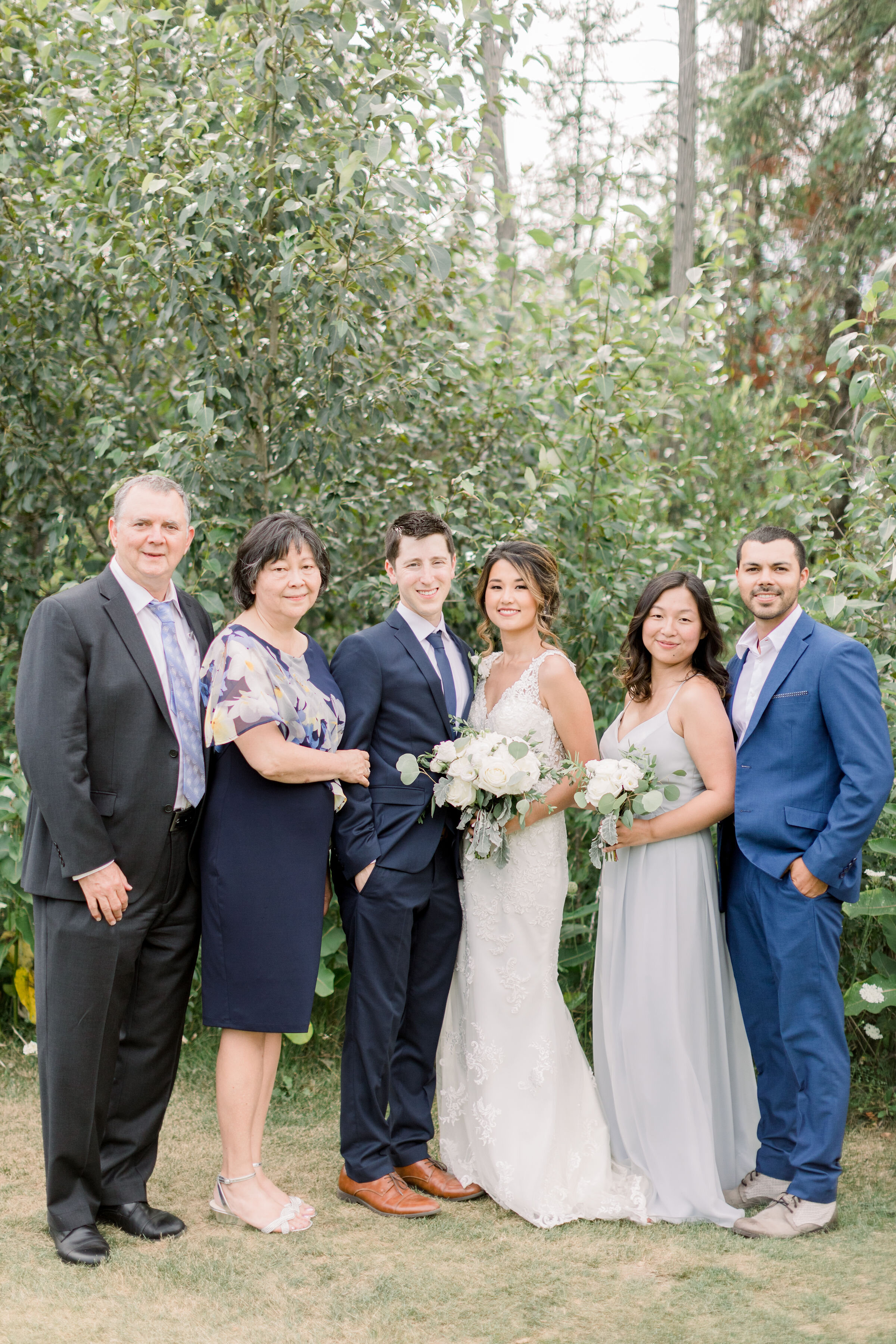  Beautiful wedding couple posing with family in an outdoor classic wedding in Ottawa, ON by Chelsea Mason Photography. how to pose large groups family pictures at weddings wedding party outfits mother of the bride outfit blue and silver wedding color