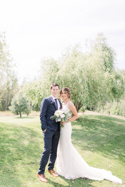  Beautiful couple in formals with navy suit and blue tie and brown shoes and bride has long lacy dress with white bouquet by Chelsea Morgan Photography in Ottawa, ON. classic wedding style how to style your groom navy suit for groom wedding dress ins