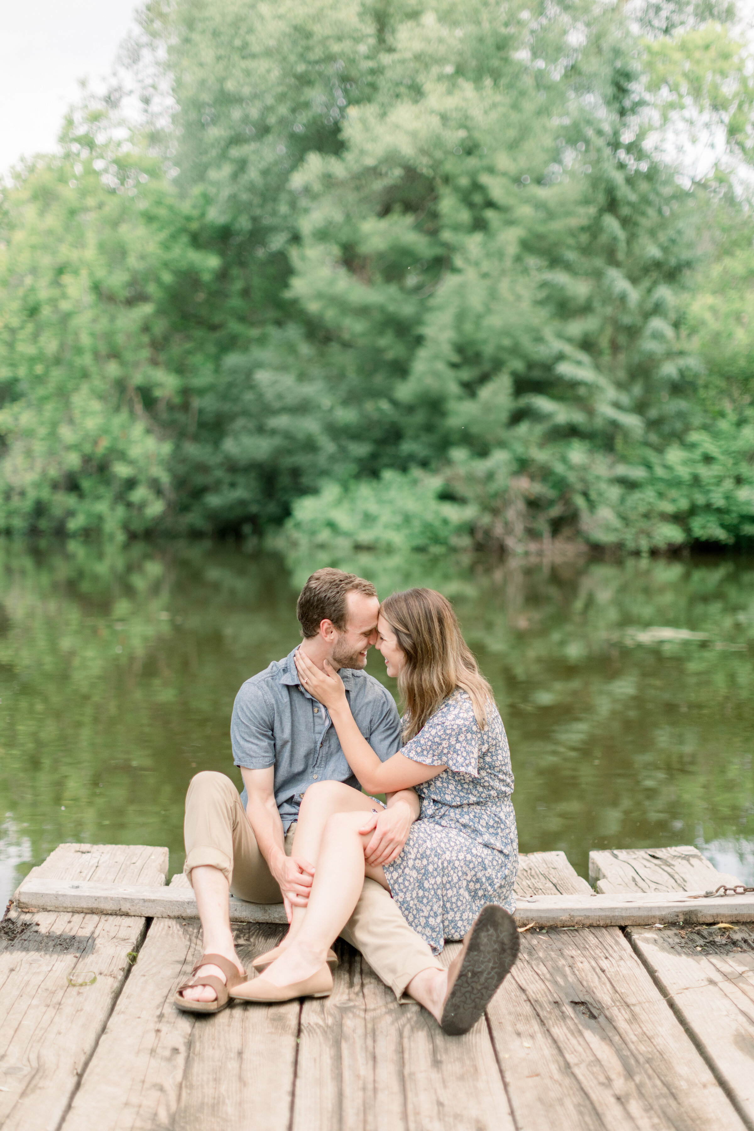  Adorable couple wearing casual outfits with Birkenstock sandals on a dock by a lake for summer engagement photoshoot by Chelsea Mason Photography in Ottawa, ON. outfit inspo for engagements casual outfits for engagements sandals for engagements can 