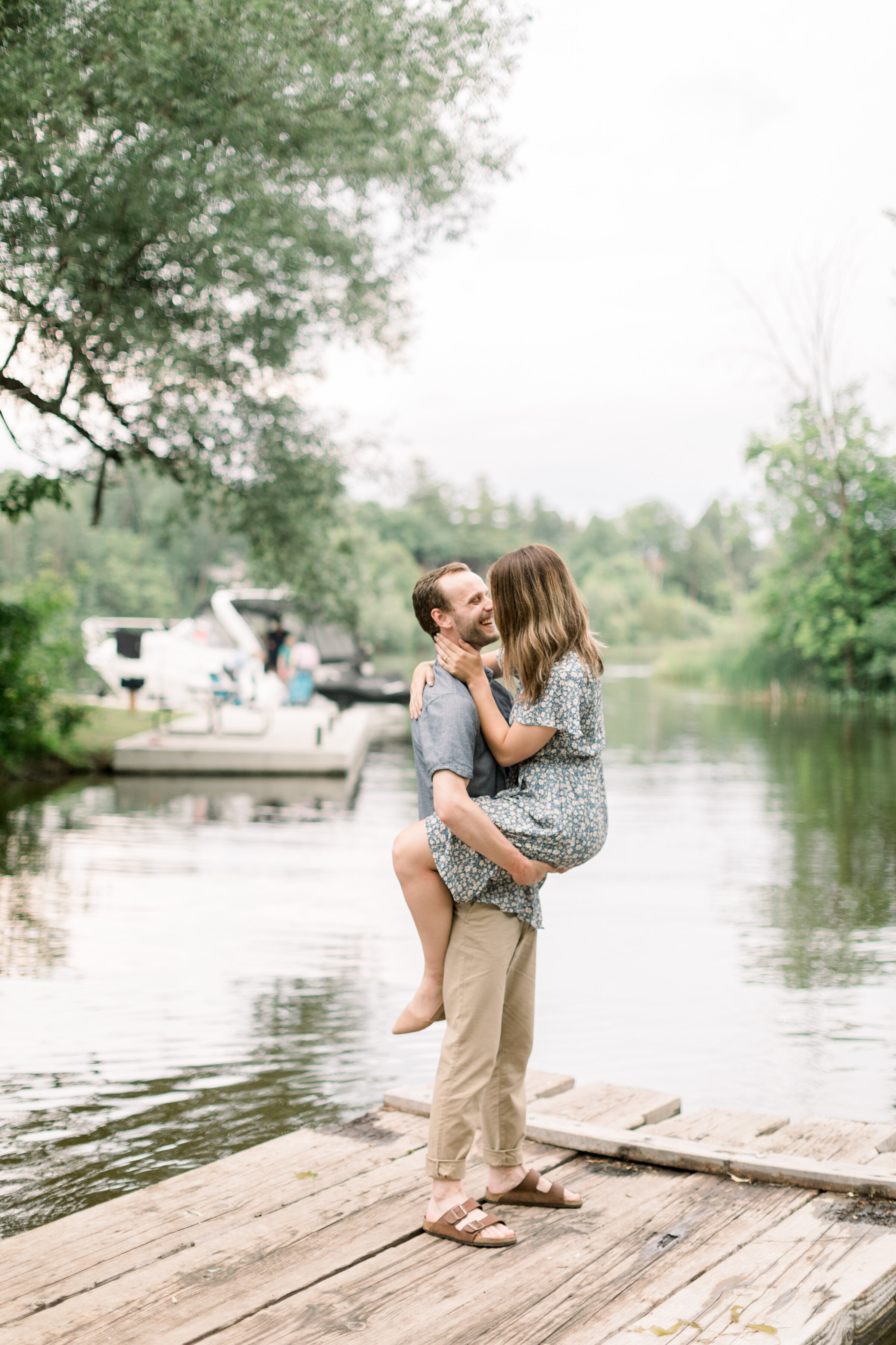  Cute pose with guy holding girl on bride with lake and boat in the background for posing inspo in Ottawa ,ON by Chelsea Mason Photography. pose inspo for engagements best poses for engagements how to pose for engagements lake locations for photoshoo