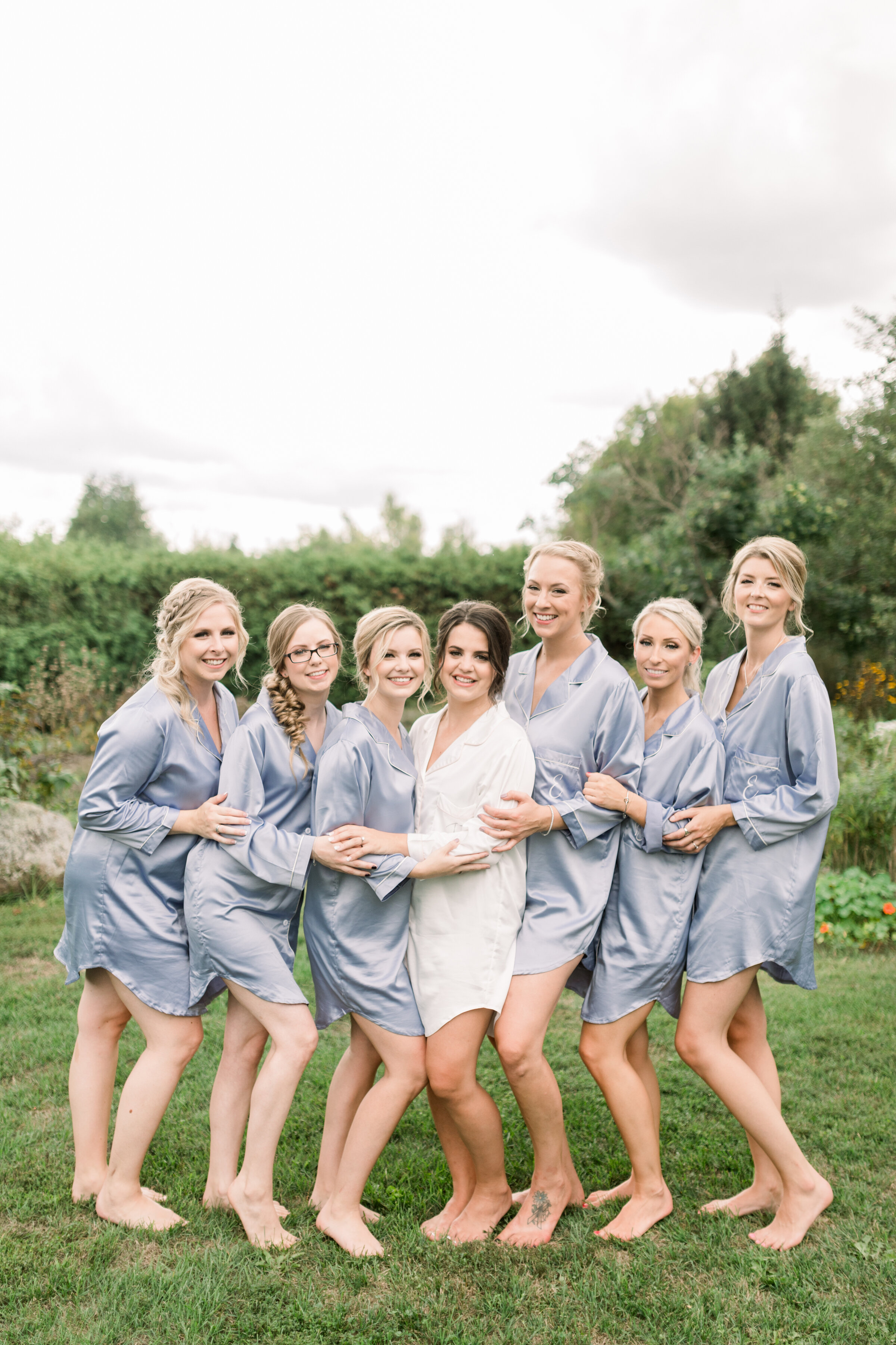  Bridal party wearing matching light blue silk pajamas making for the perfect bridesmaid gift by Chelsea Mason Photography in Ottawa, ON. herb garden wedding venue perfect outdoor wedding venue in carleton place what gift should i get my bridesmaids 
