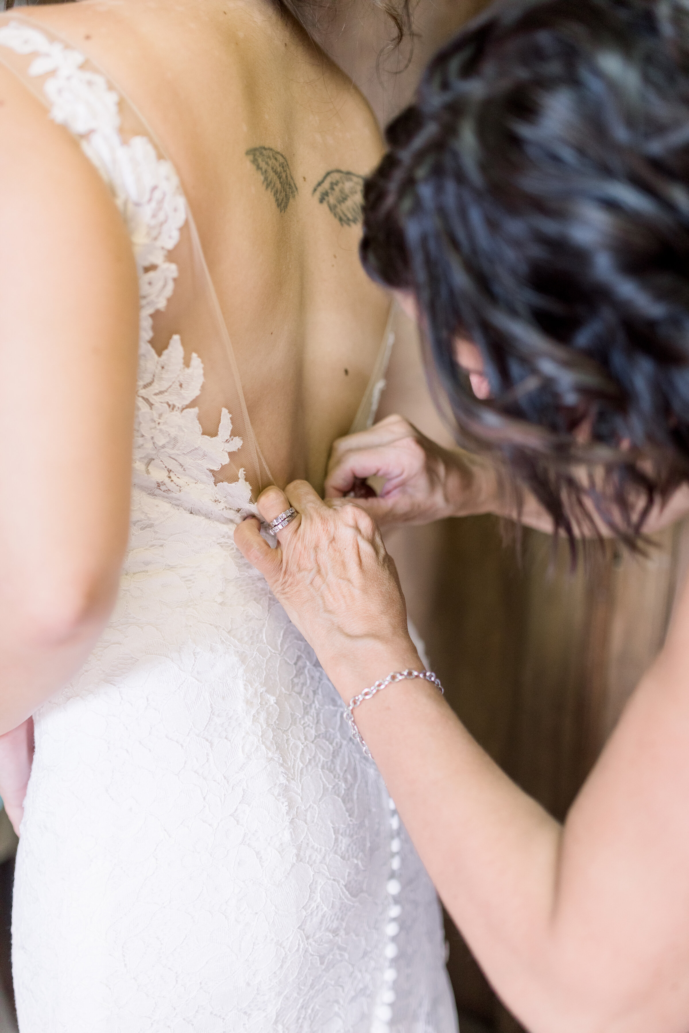  Bride with lace dress and lots of detail buttons going up the back with angel wing tattoos in Ottawa, ON by Chelsea Mason Photography. back of wedding dress backless wedding dress tattoos on wedding day angel wing tattoo brides with tattoos should i