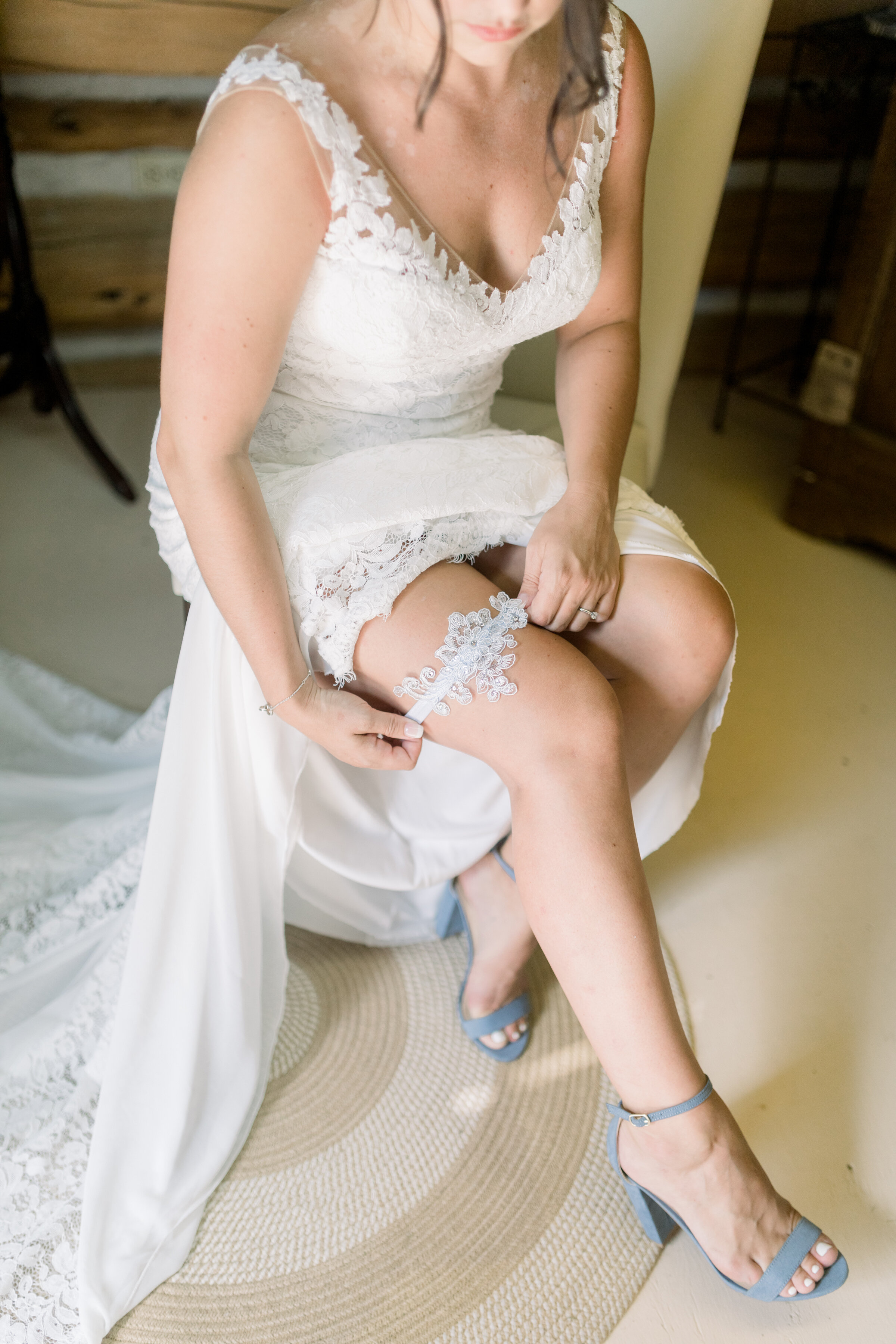  Bride putting on beautiful lace garter for outfit inspo on your wedding day at The Herb Garden by Chelsea Mason Photography. should i wear a garter to my wedding garter inspo best garters for wedding how should i wear my garter on my wedding day out