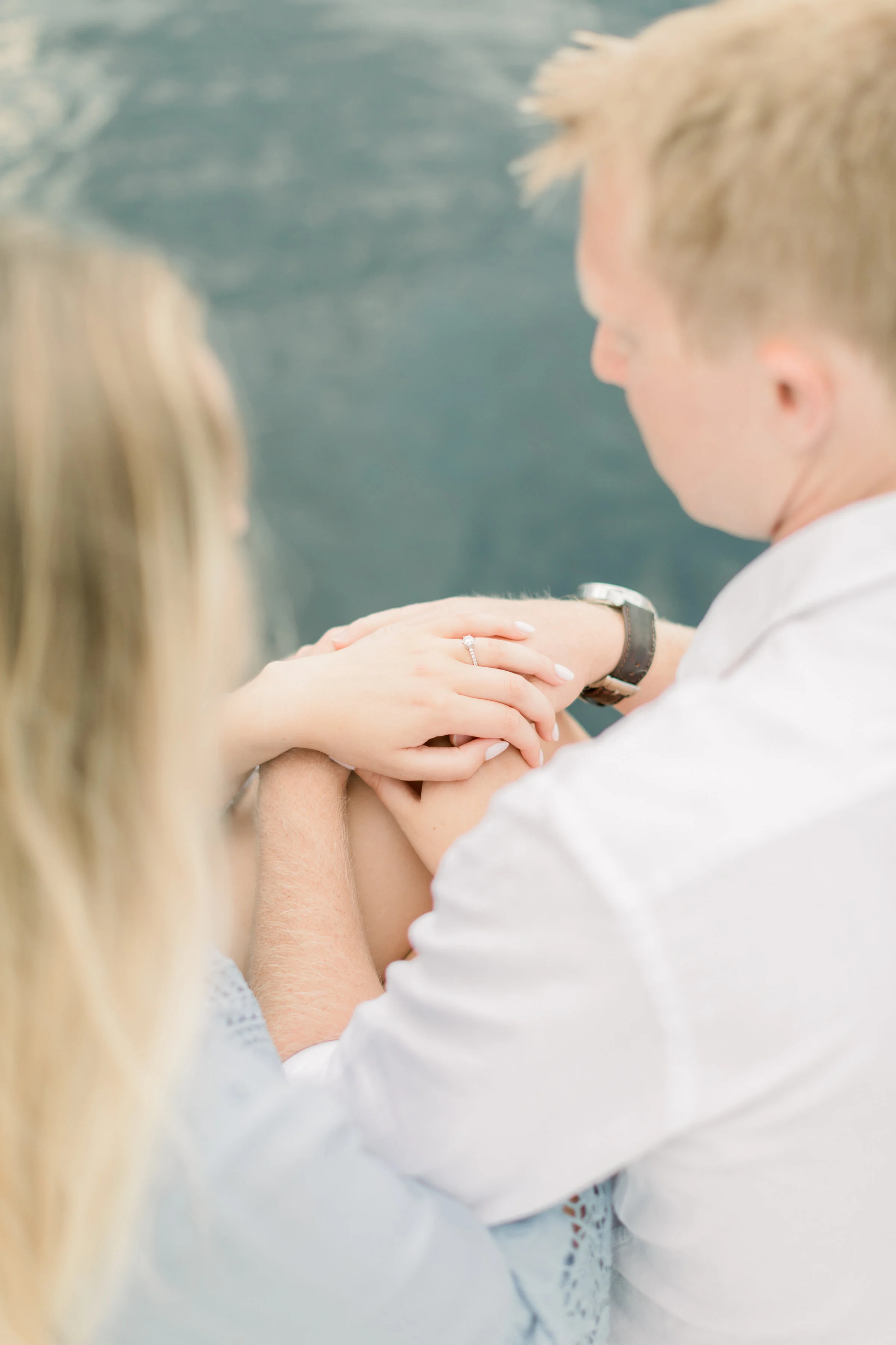 Couple looking at the engagement ring on a boat at a lake in this outdoor photoshoot by Chelsea Mason Photography in Ottawa, ON. how to pose couples shooting engagement rings inspo outfit inspo for engagement photos lake locations in ottawa photogra