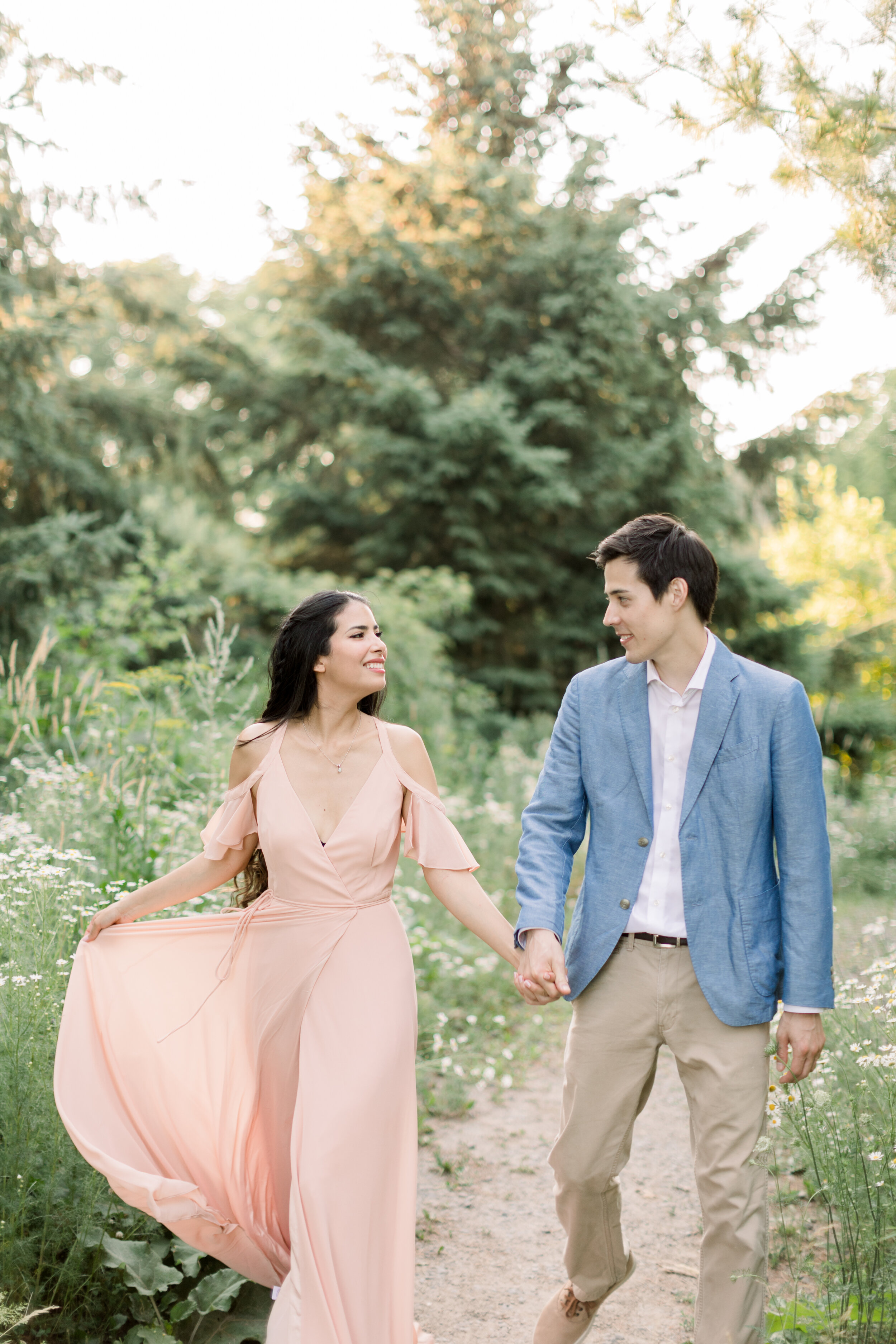  Beautiful couple wearing a floor-length flowing blush pink dress and a light blue blazer in Ottawa, ON by Chelsea Mason Photography. how to style for engagements pink for engagements should i wear a dress for engagements dress or pants for engagemen
