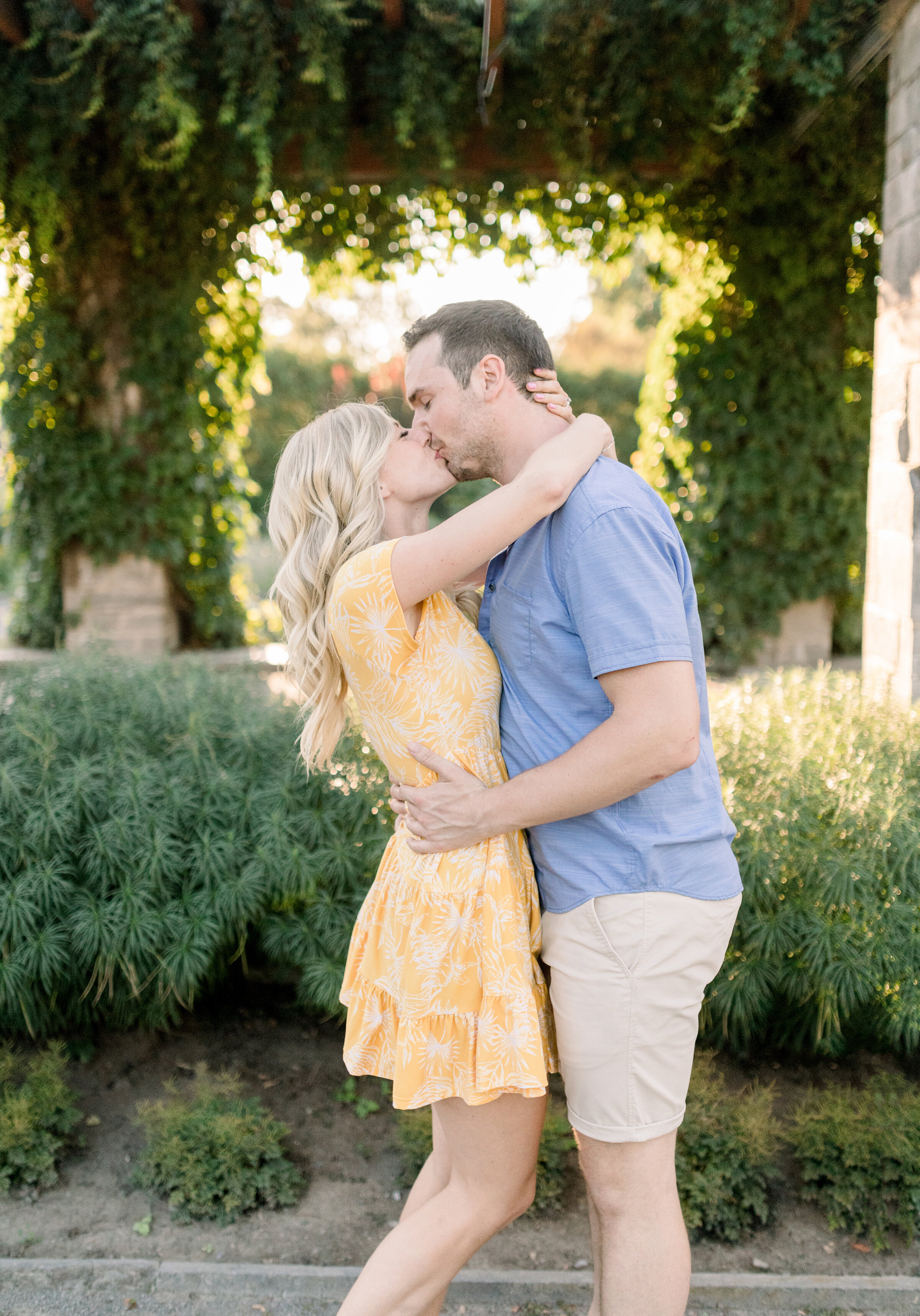  A glowing couple kiss under the vines at the Botanical Garden in a beautiful engagement session by Chelsea Mason Photography. Engagement session inspiration Montreal Canada photo shoot location ideas professional engagement photographer  couple pose