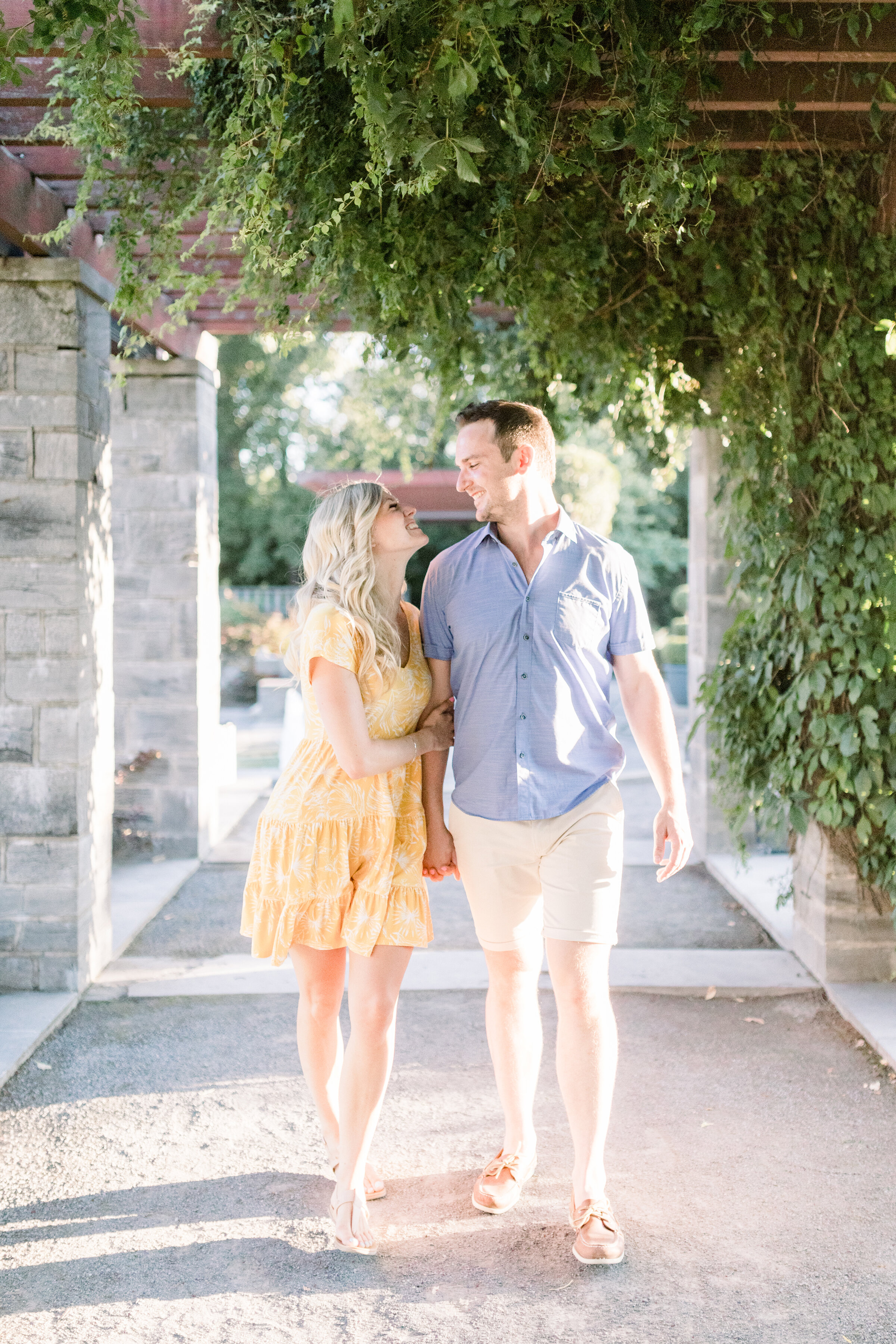  A glowing couple walk through a vine covered terrace in a beautiful Botanical Garden styled engagement photo shoot by Chelsea Mason Photography. Engagement session goals couple goals couple pose inspiration ideas and goals sundress goals spring enga