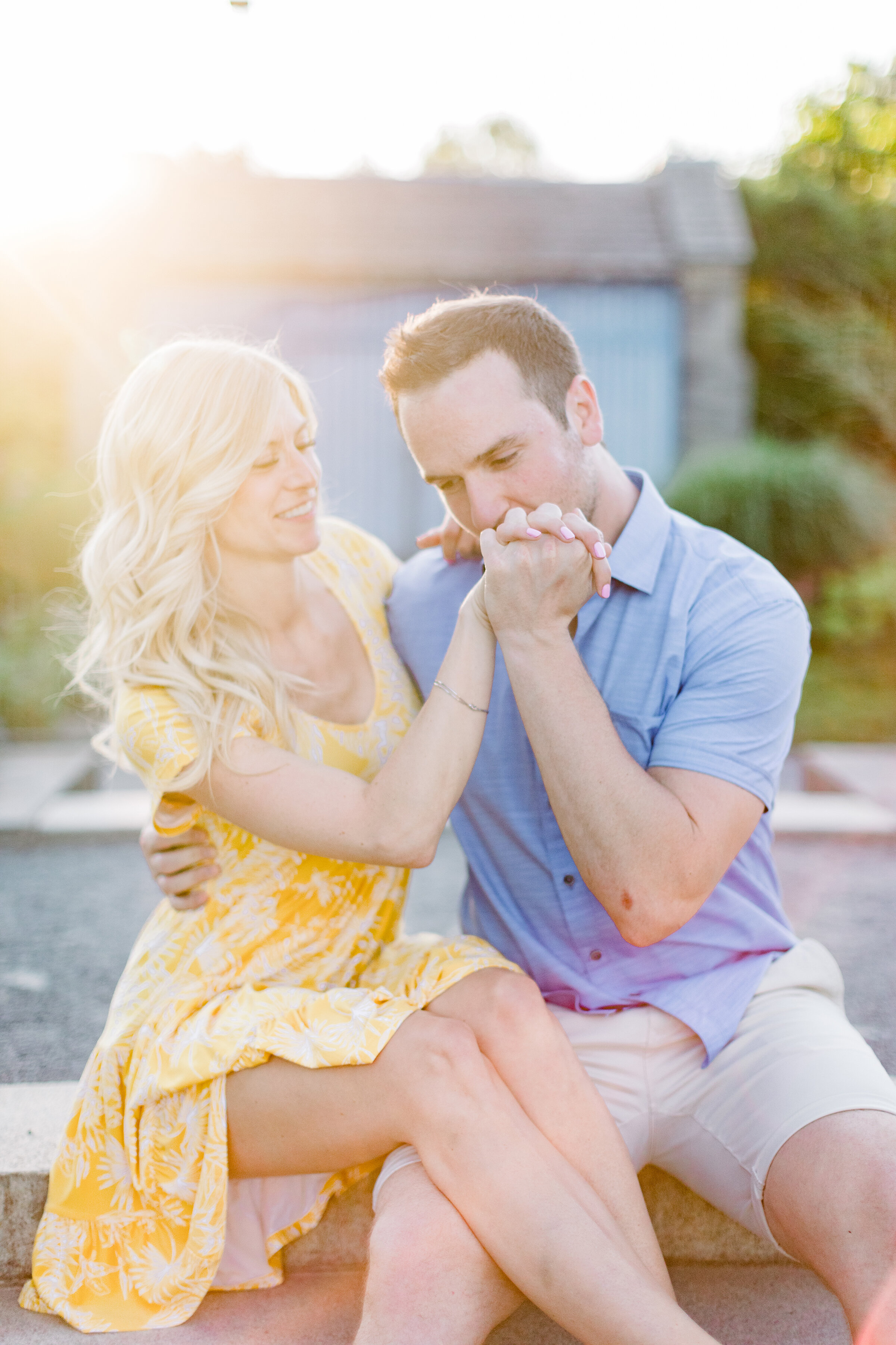  A gentleman kisses his fiancés hand in a beautiful bright and airy engagement session at the Botanical Garden in Montreal Canada. Chelsea Mason Photography sitting couple pose inspiration glowing couple professional engagement photographer location 