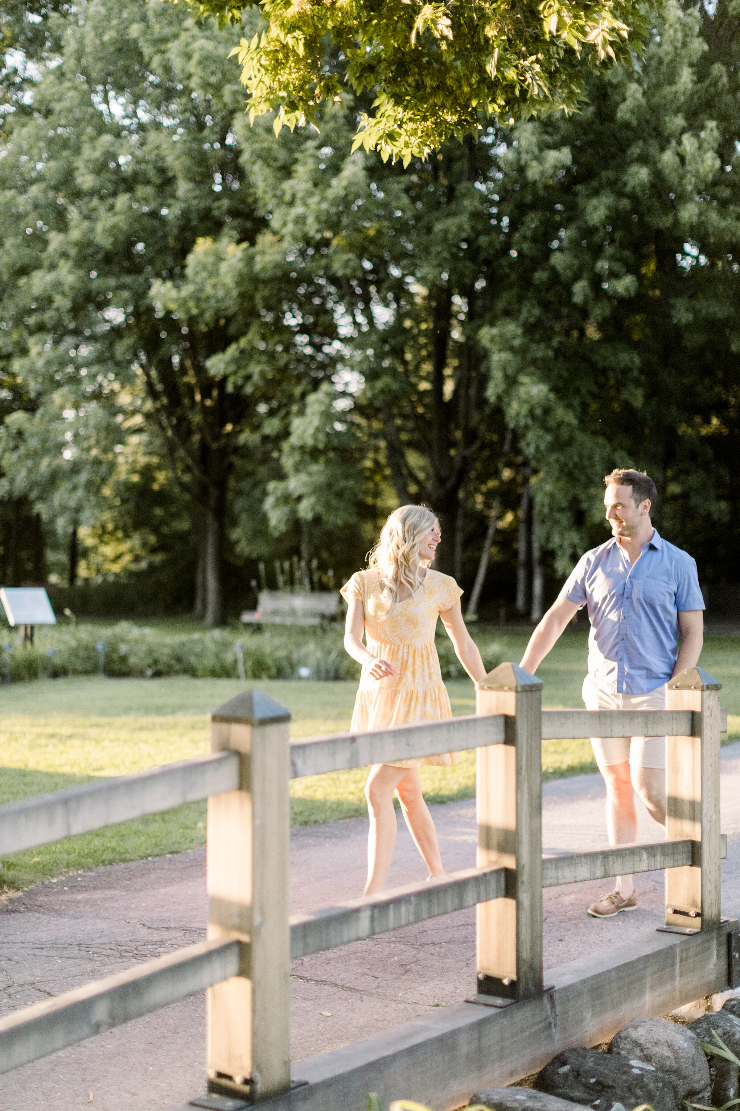  A couple hold hands as they walk across a wooden bridge in the beautiful Botanical Gardens of Montreal Canada. Professional engagement photographer Chelsea Mason Photography outdoor engagement session inspiration ideas and goals summer engagement se