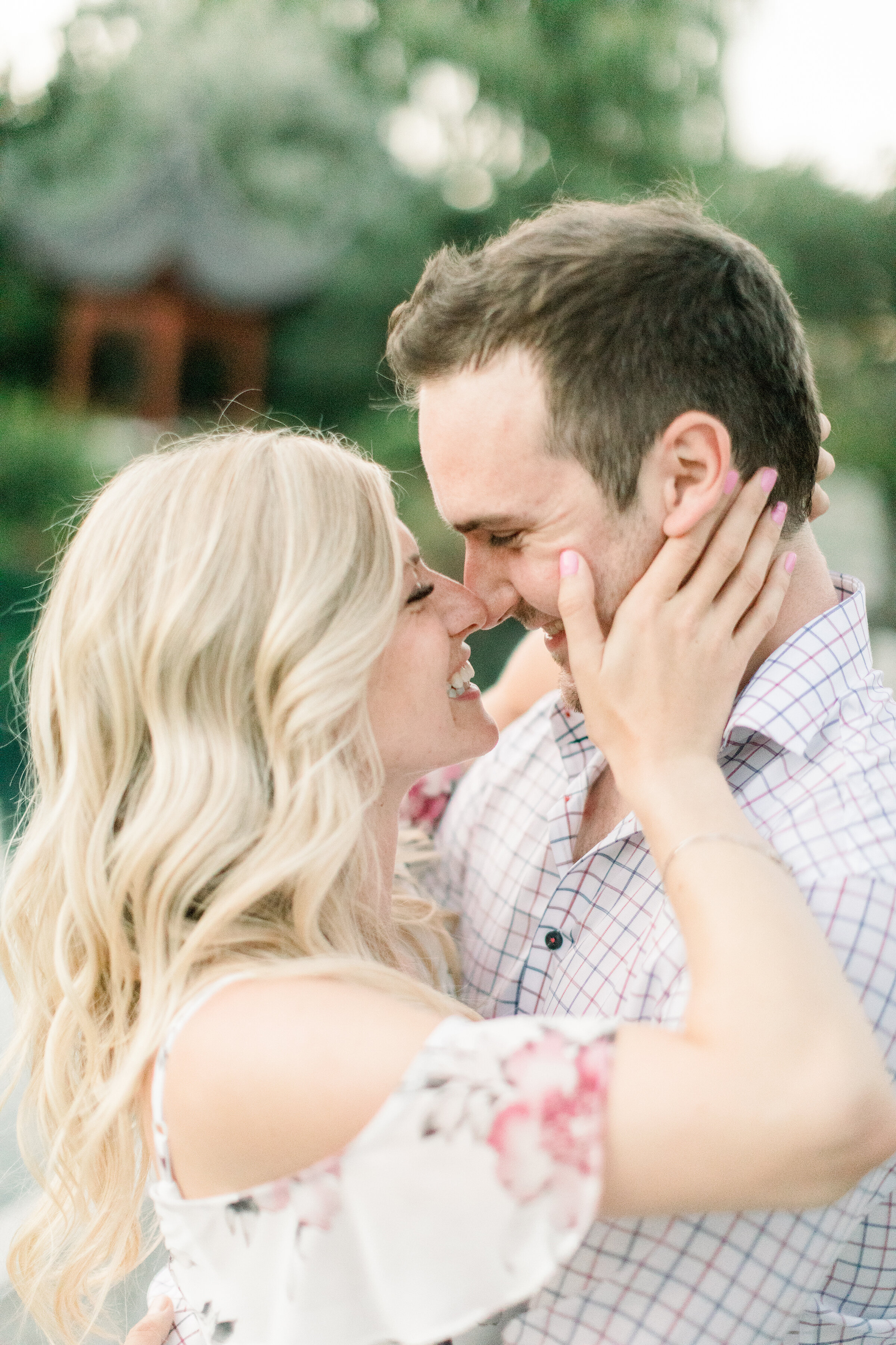  A women holds her fiancés face as she goes in for a kiss in a beautiful romantic engagement session by Chelsea Mason Photography. Montreal Canada Botanical Gardens outdoor engagement session close up couple pose inspiration ideas and goals engagemen