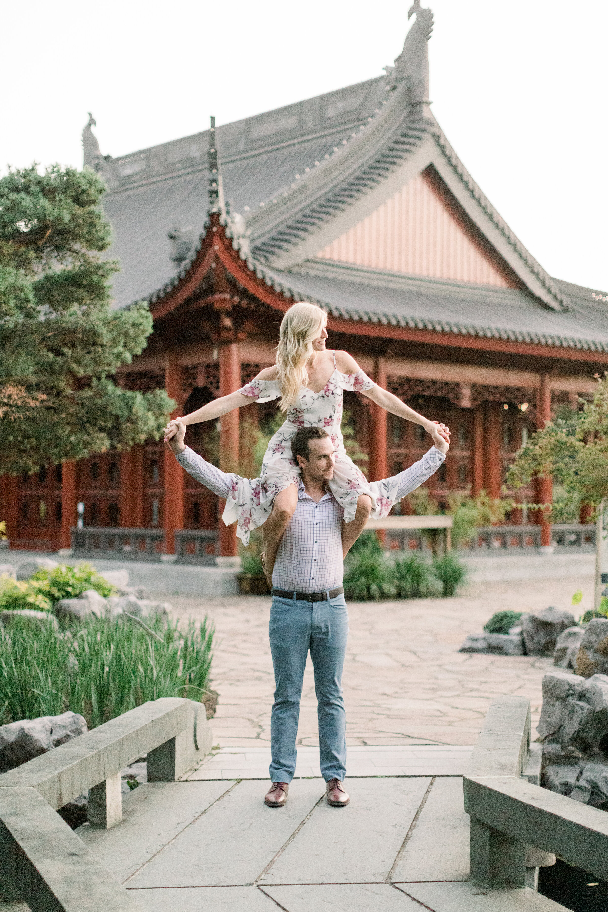  A women sits on her fiancés shoulders in a fun filled engagement session at the Botanical Gardens in Montreal, Canada. Professional engagement photographer Chelsea Mason Photography unique couple pose inspiration ideas and goals couple goals semi fo