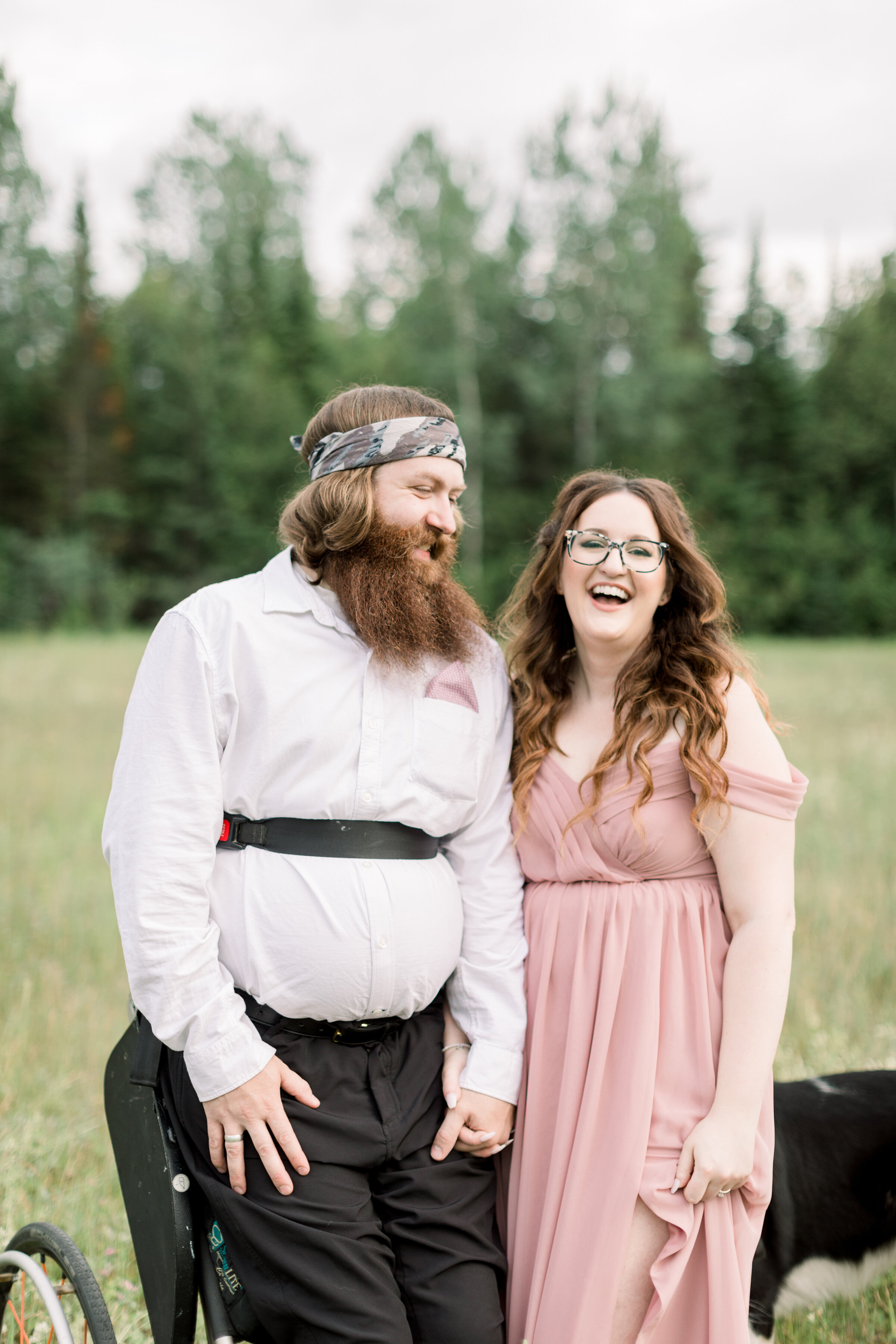  A beautiful couple laugh together in a grassy field in Smith Falls, Ontario, Canada in a rustic engagement session by Chelsea Mason Photography. Standup chair client attire inspiration ideas and goals paraplegic engagement session men's semi formal 